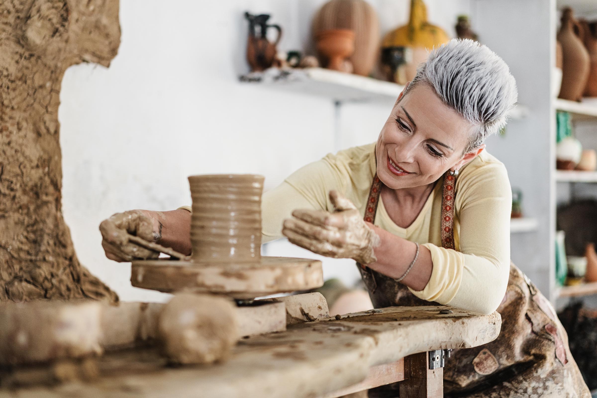 mujeres, haciendo cerámica de barro en un torno de alfarería en el estudio de arte | Fuente: Getty Images