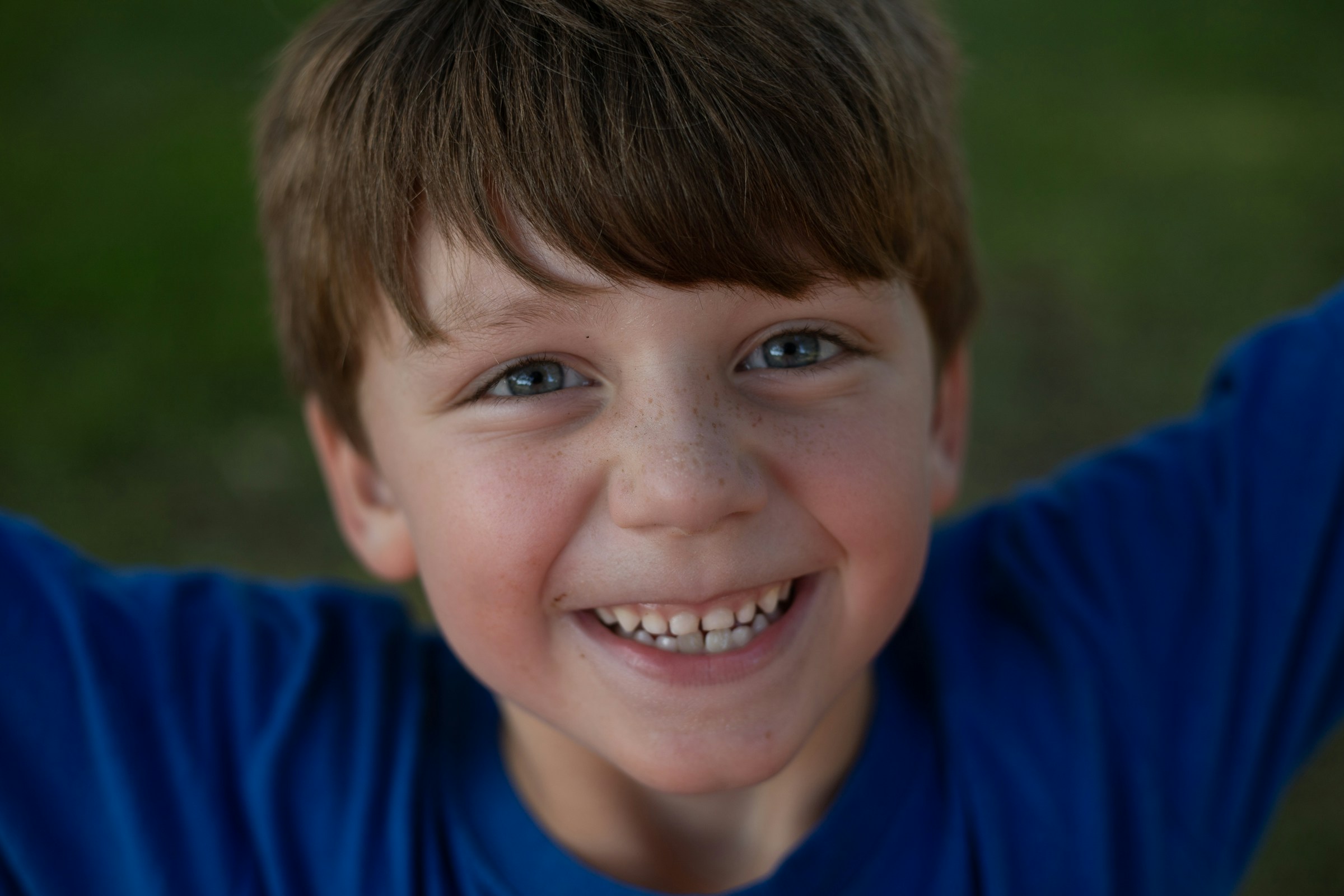 Un niño sonriente con una camisa azul | Fuente: Unsplash