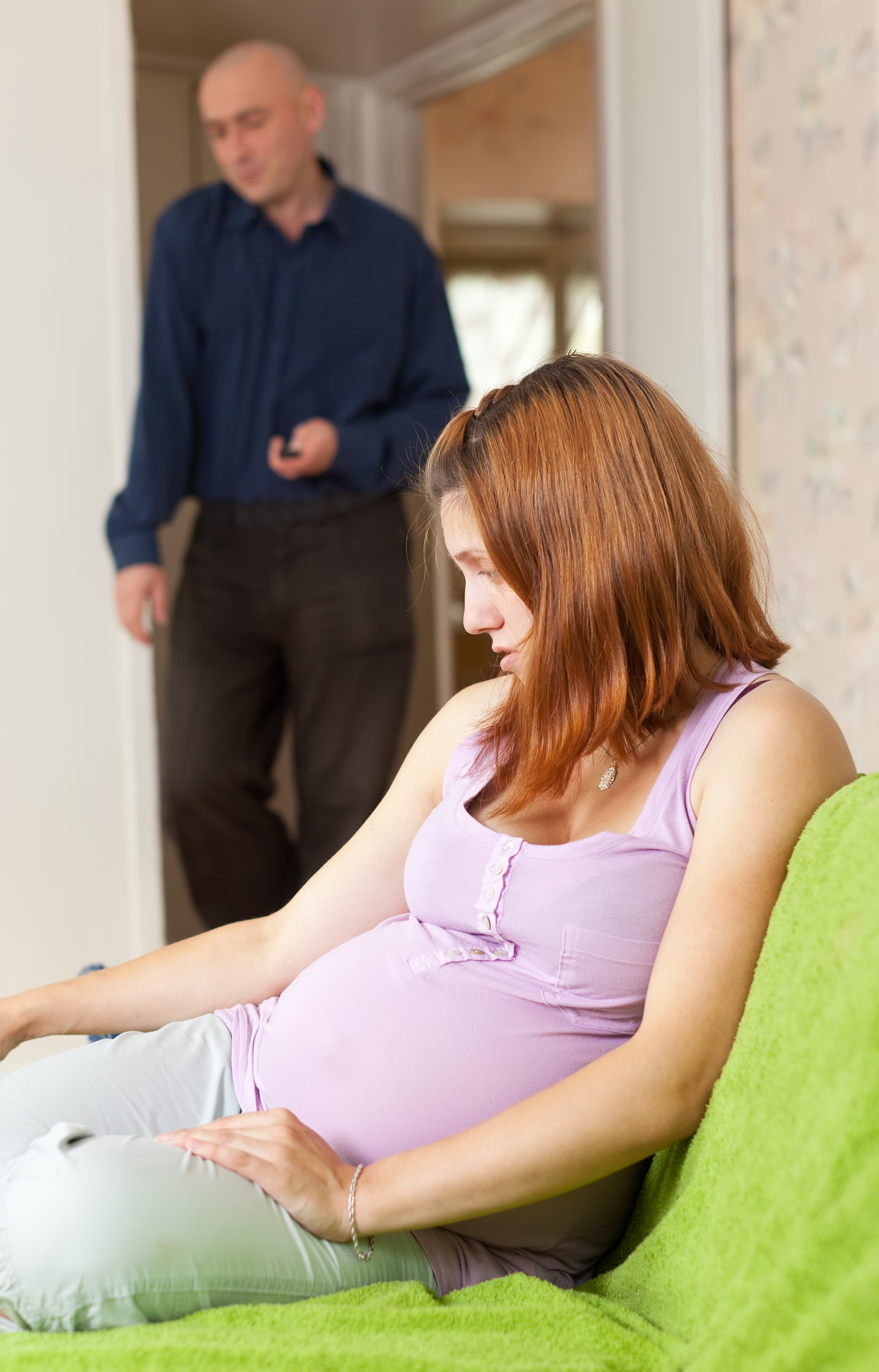 Mujer embarazada y un hombre al fondo | Fuente: Shutterstock