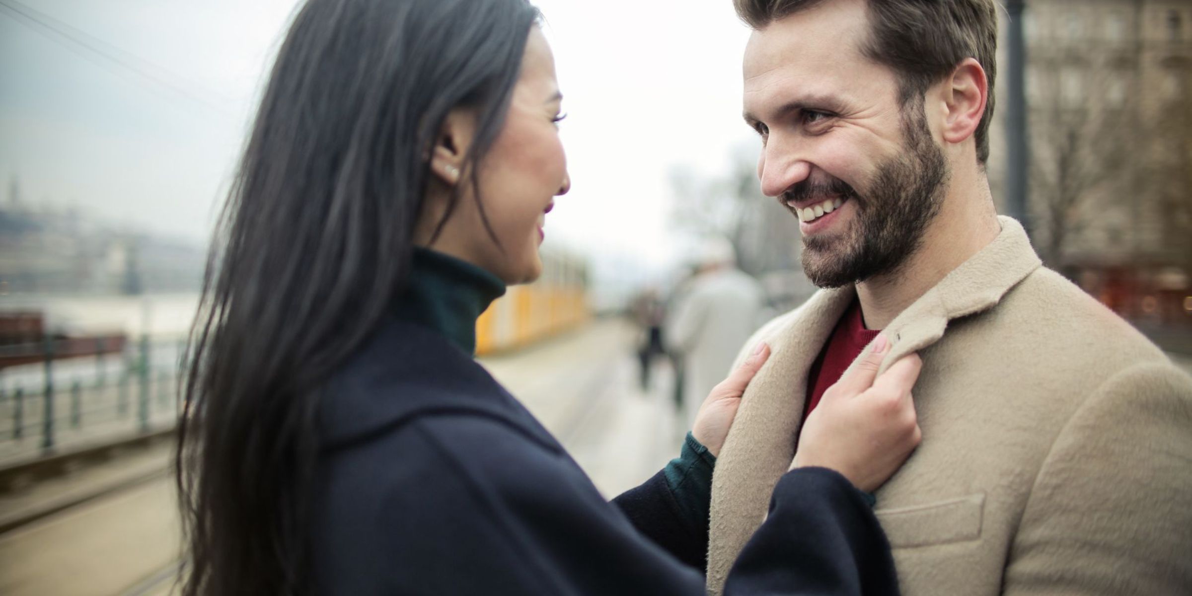 Una mujer arreglando el abrigo de un hombre | Fuente: Pexels