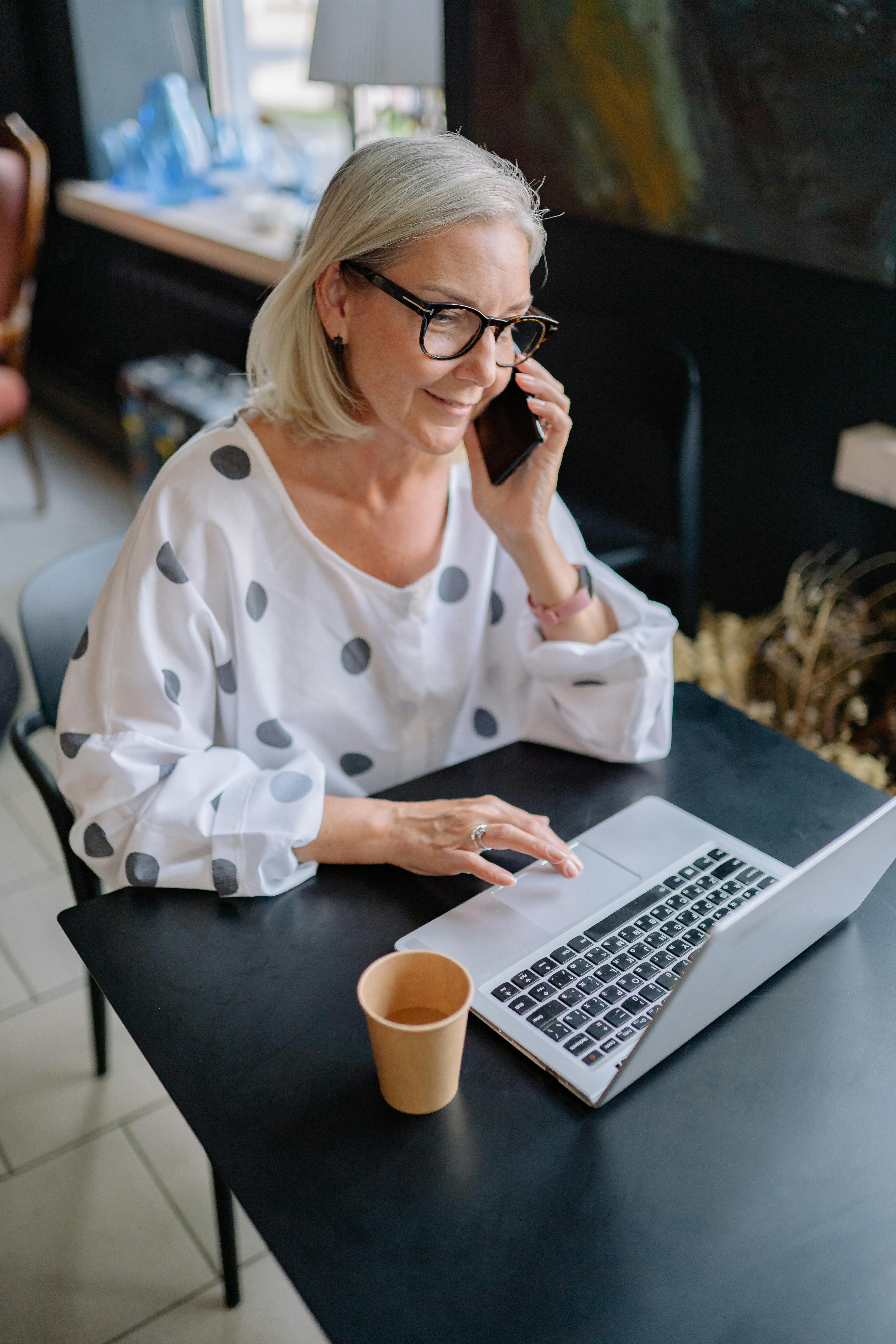 Una mujer utilizando su teléfono y su portátil simultáneamente | Fuente: Pexels