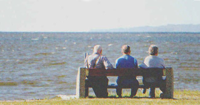 Drei ältere Männer sitzen auf einer Bank am Meer | Quelle: Shutterstock