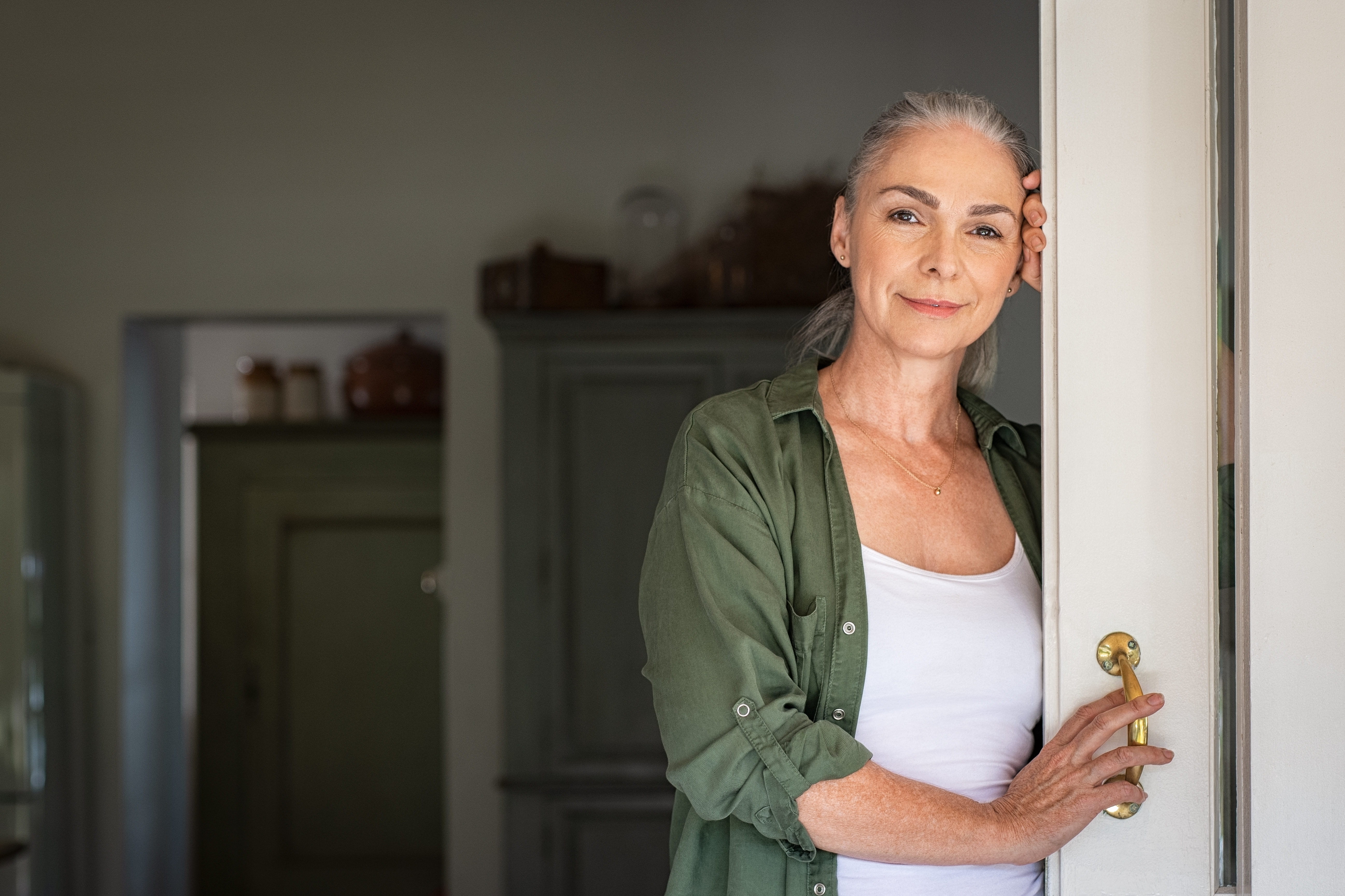 Retrato de mujer mayor apoyada en la puerta | Fuente: Shutterstock