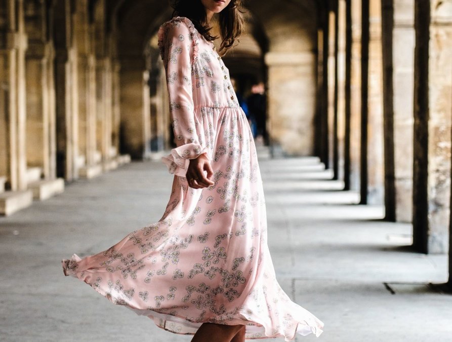 Mujer joven vistiendo un traje rosa caminando por los pasillos de una iglesia. | Imagen: Pixnio