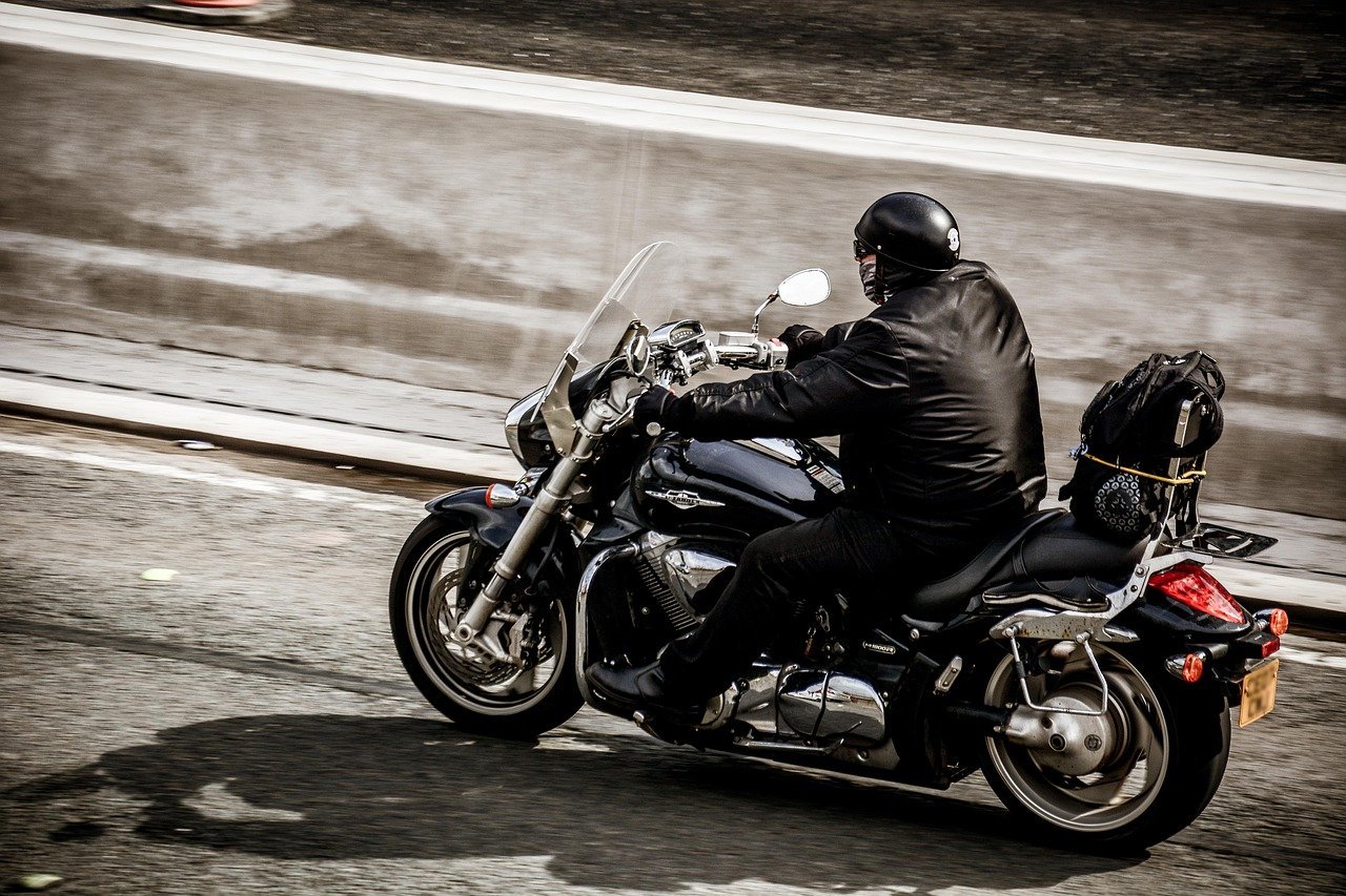 Motociclista vestido de negro conduciendo su motocicleta por una carretera de asfalto. | Imagen: Needpix.com