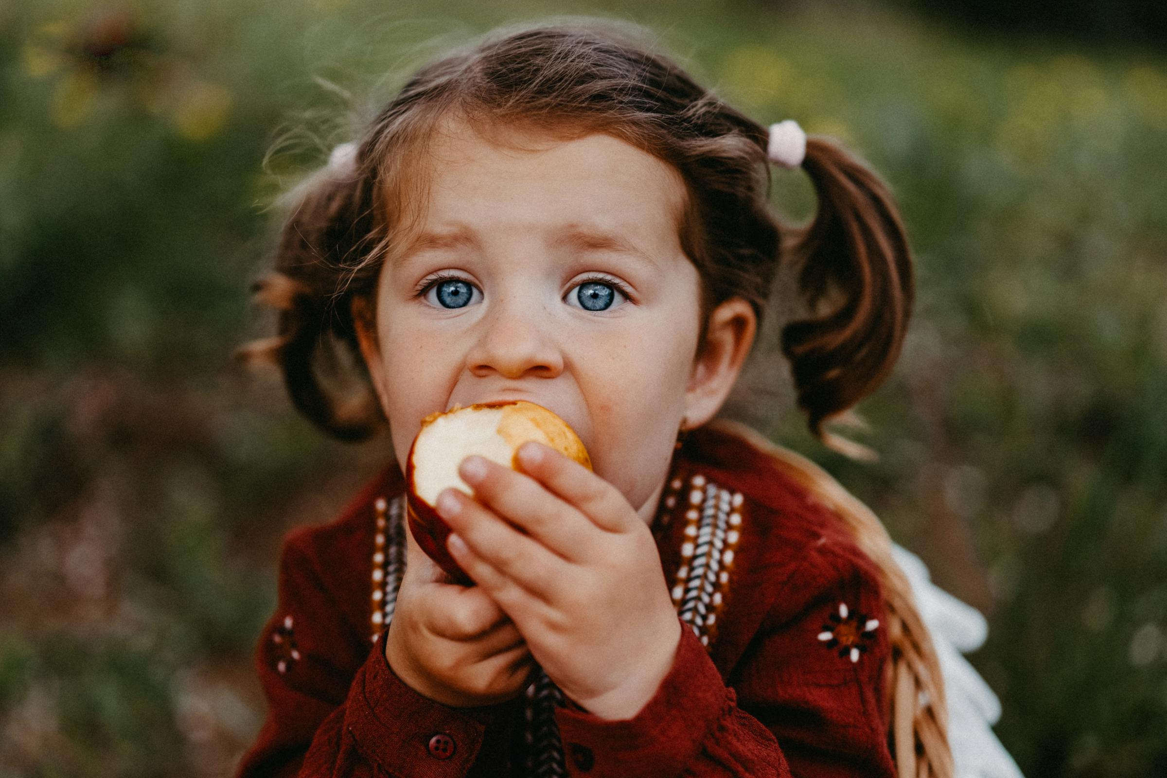 Una niña comiendo una manzana | Fuente: Pexels