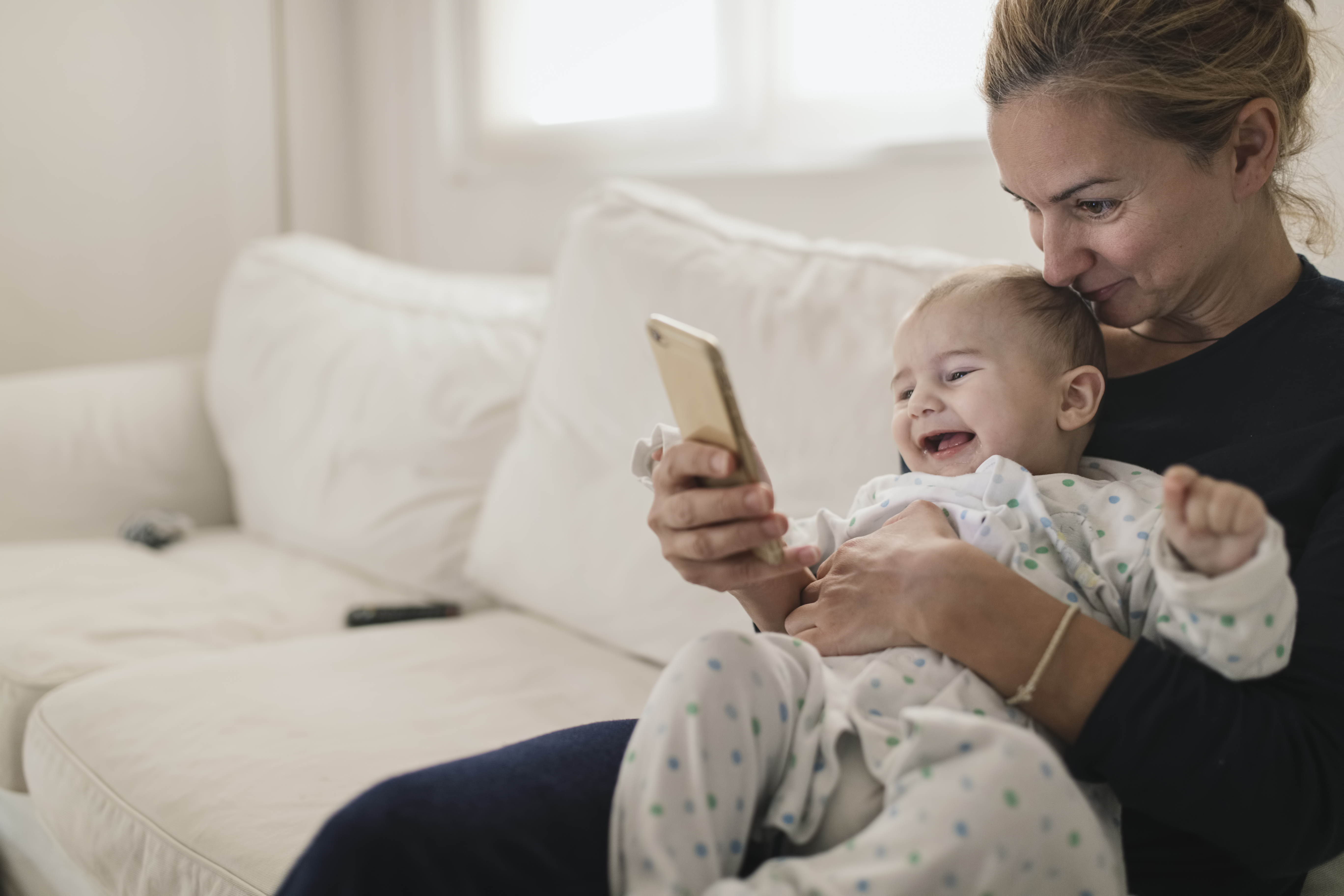 Madre sujetando a su bebé mientras mira su teléfono móvil | Foto: Getty Images