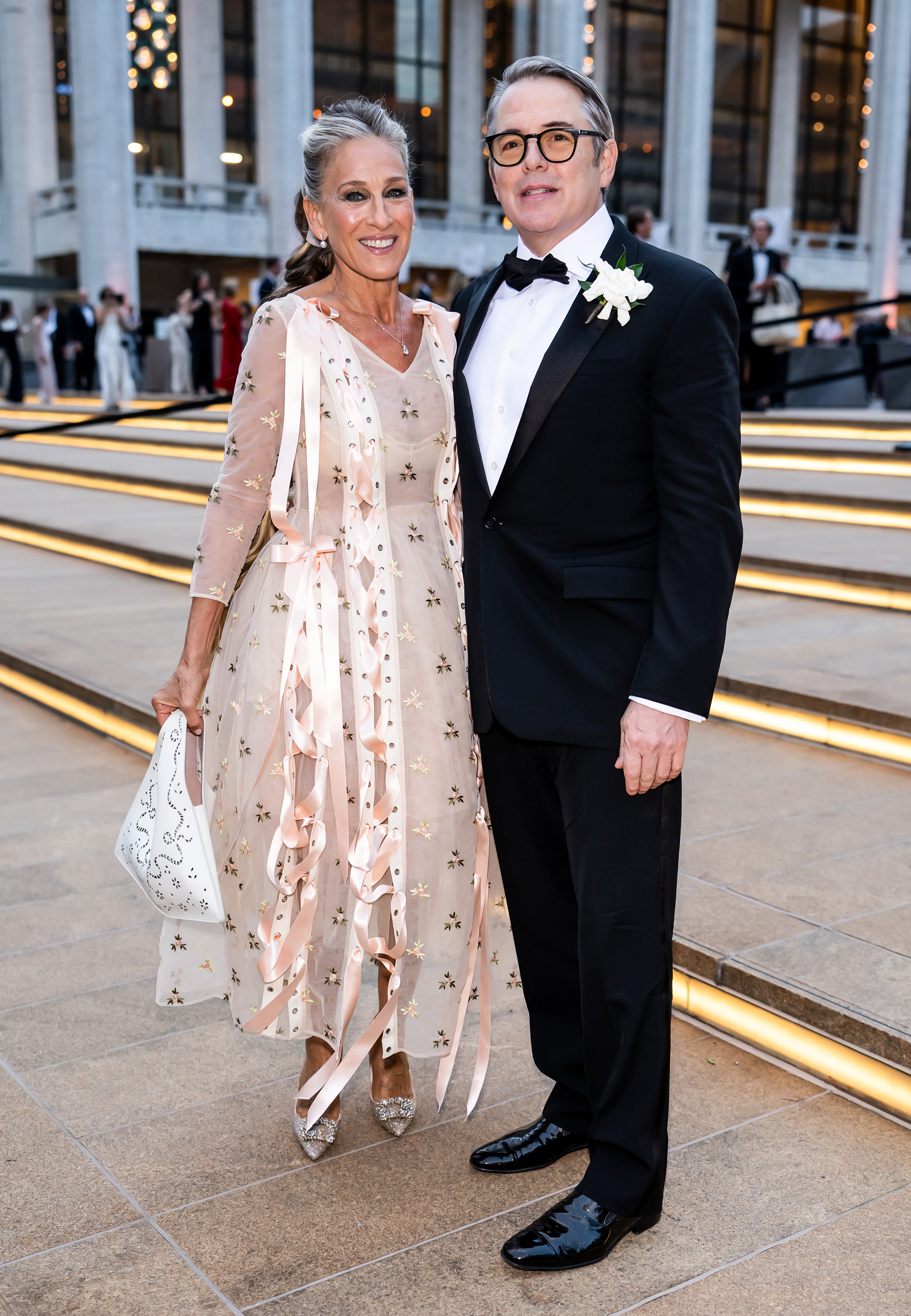 Parker y Broderick posan frente al Lincoln Center, donde el contraste es sorprendente: su delicado diseño bordado contrasta con el clásico esmoquin negro de él y su flor en el ojal. | Fuente: Getty Images