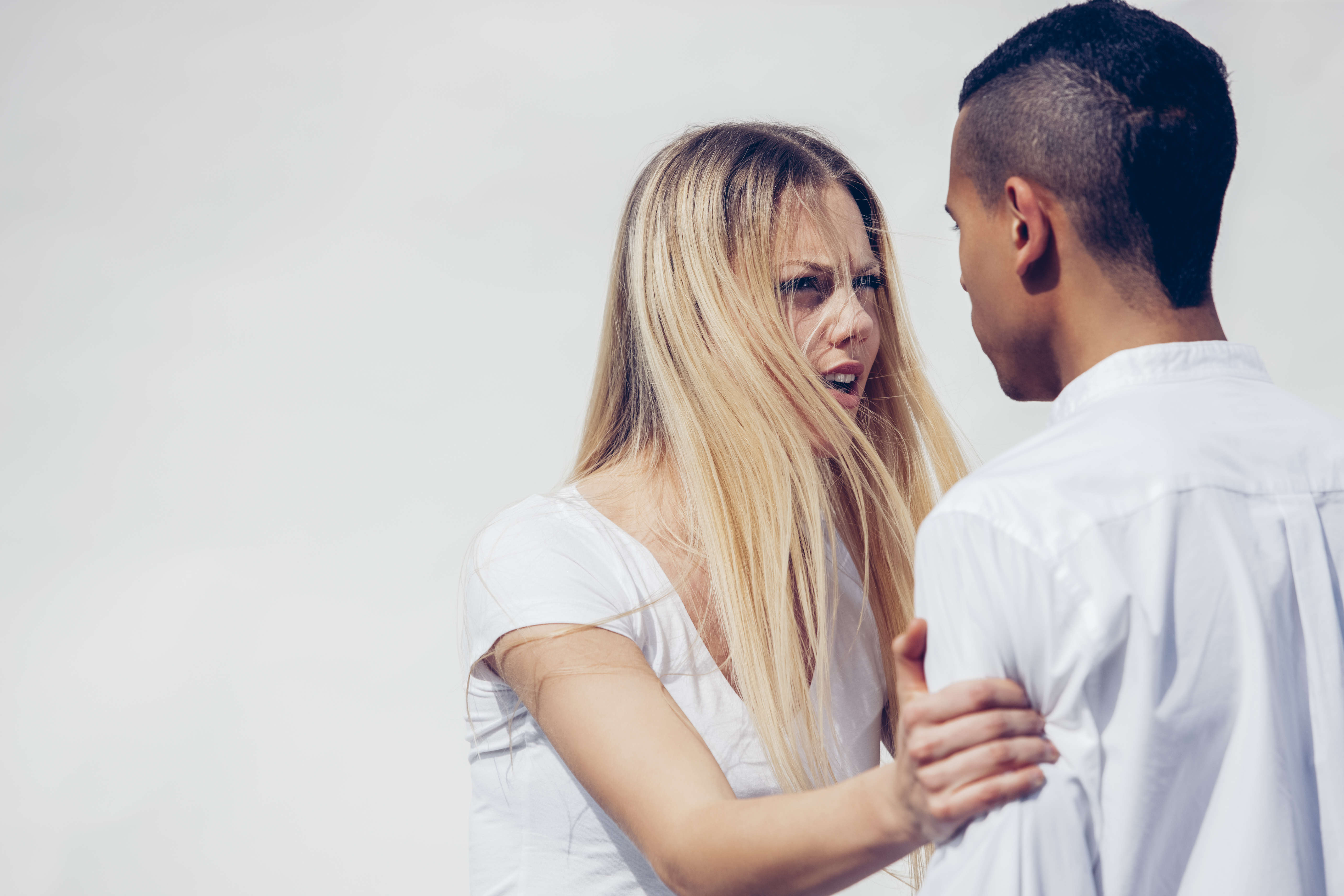 Retrato de joven enfadada cara a cara con su novio delante de un fondo blanco | Foto: Getty Images