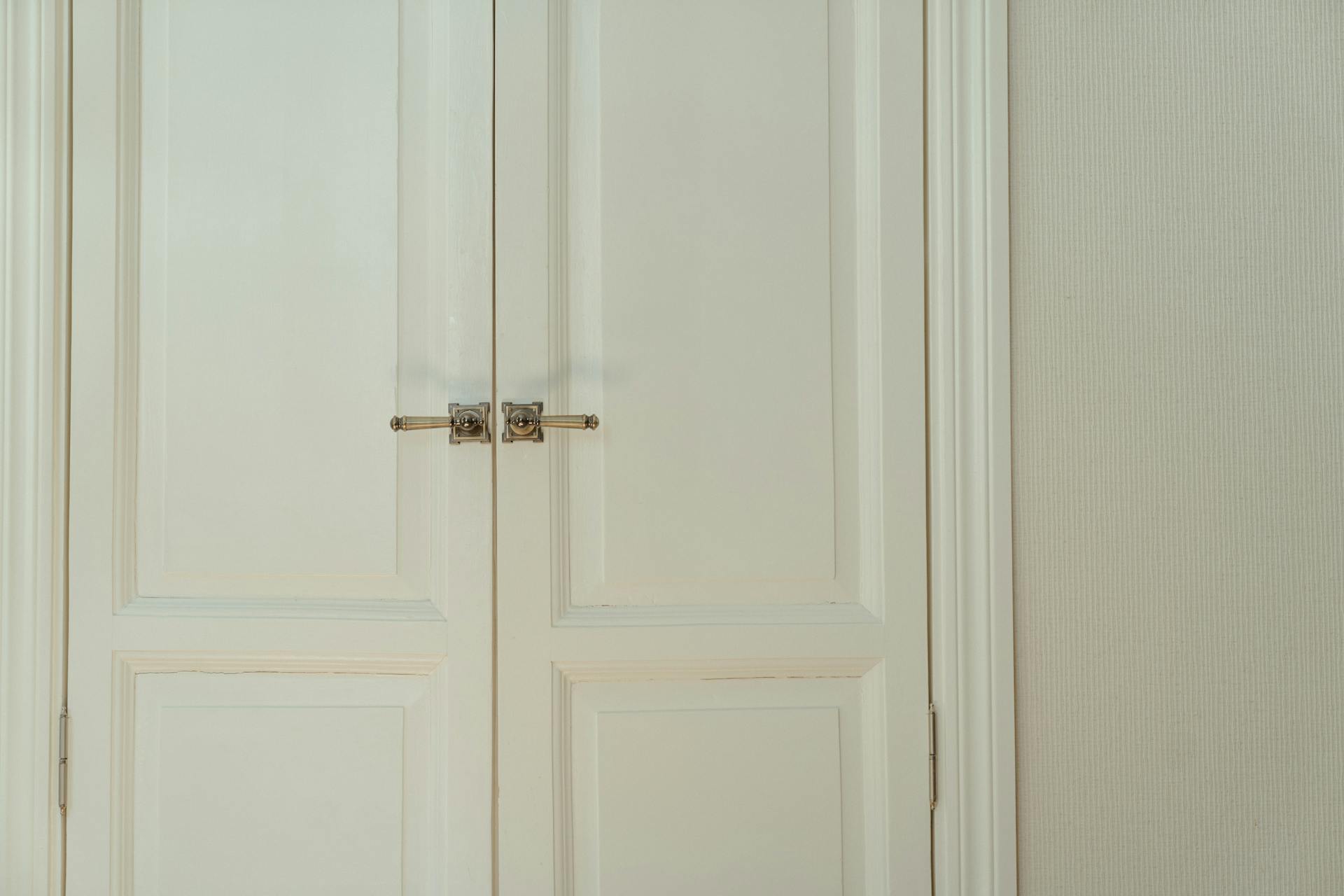 Una puerta de madera blanca con picaportes plateados | Fuente: Pexels