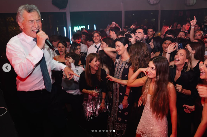 Mauricio Macri toma el micrófono sobre el escenario para cantar animadamente frente a los invitados. A su lado, Antonia Macri sonríe y baila rodeada de amigos y familiares en medio de la pista de baile. | Fuente: Instagram/mauriciomacri