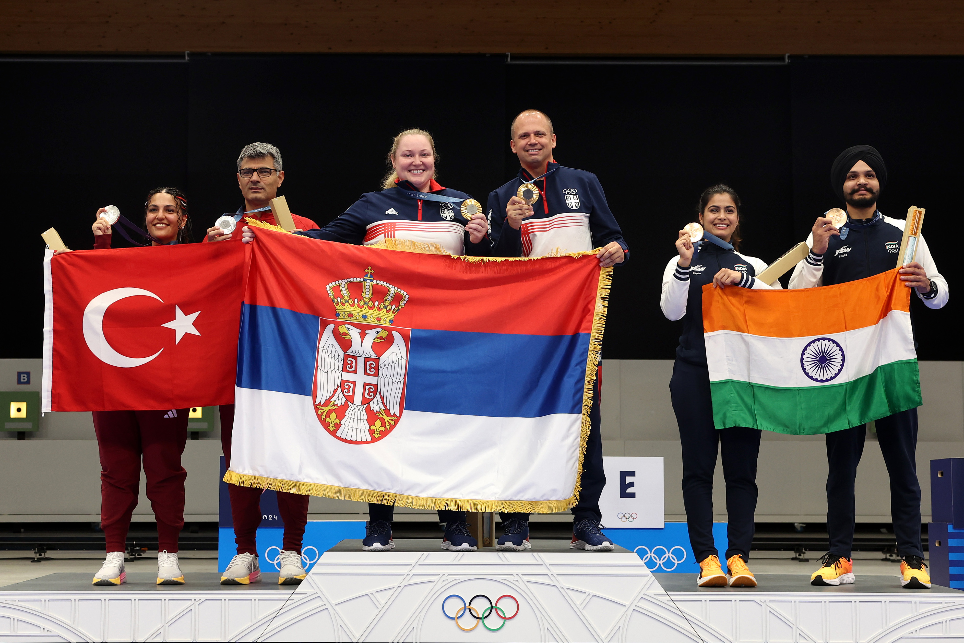 Sevval Ilayda Tarhan y Yusuf Dikeç, Zorana Arunovic y Damir Mikec, y Manu Bhaker y Sarabjot Singh posan en el podio durante la ceremonia de entrega de medallas del Equipo Mixto de Tiro con Pistola de Aire 10m en los Juegos Olímpicos de París el 30 de julio de 2024, en Chateauroux, Francia | Fuente: Getty Images