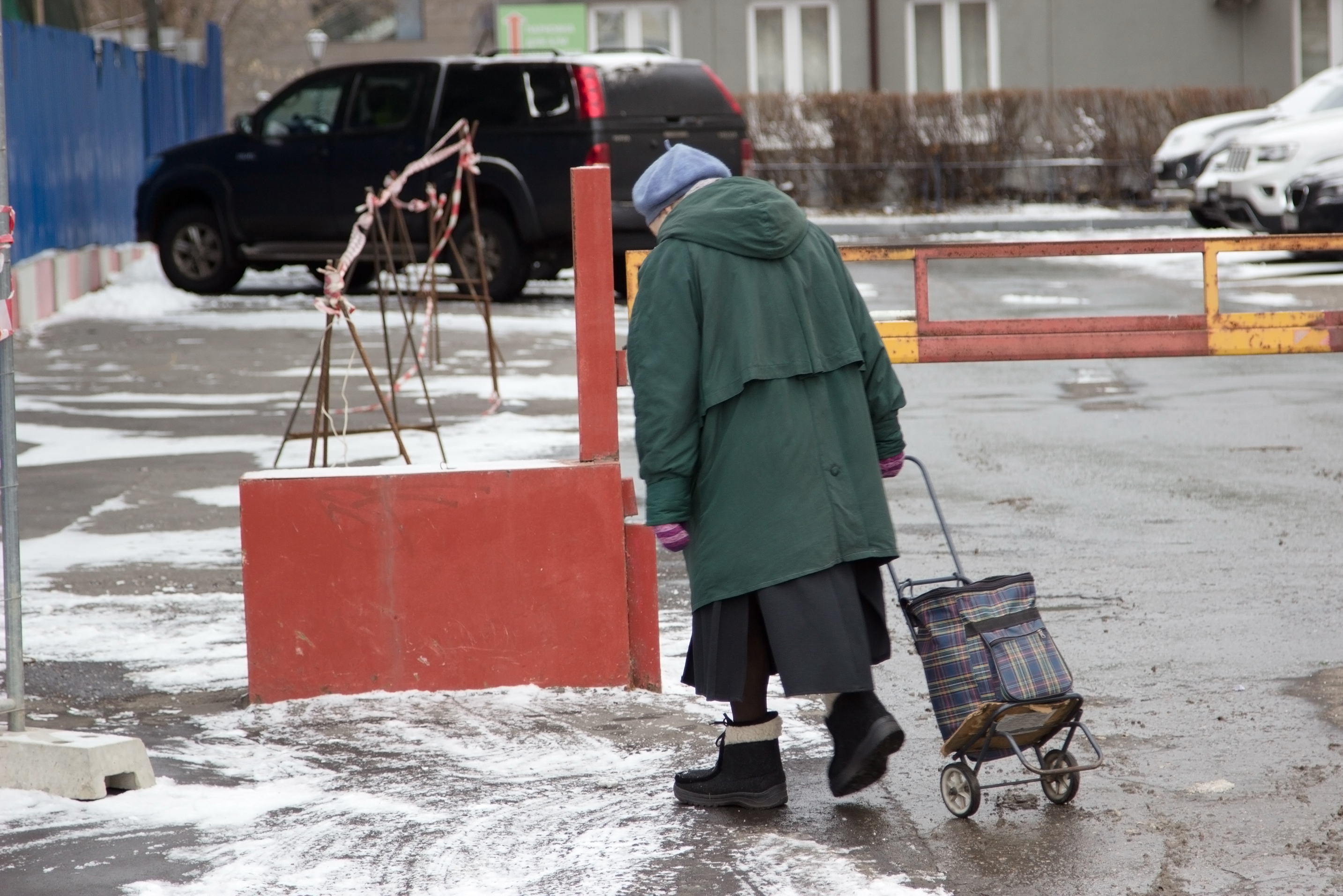 Einsame ältere Dame, die auf einer verschneiten Straße spazieren geht | Quelle: Shutterstock