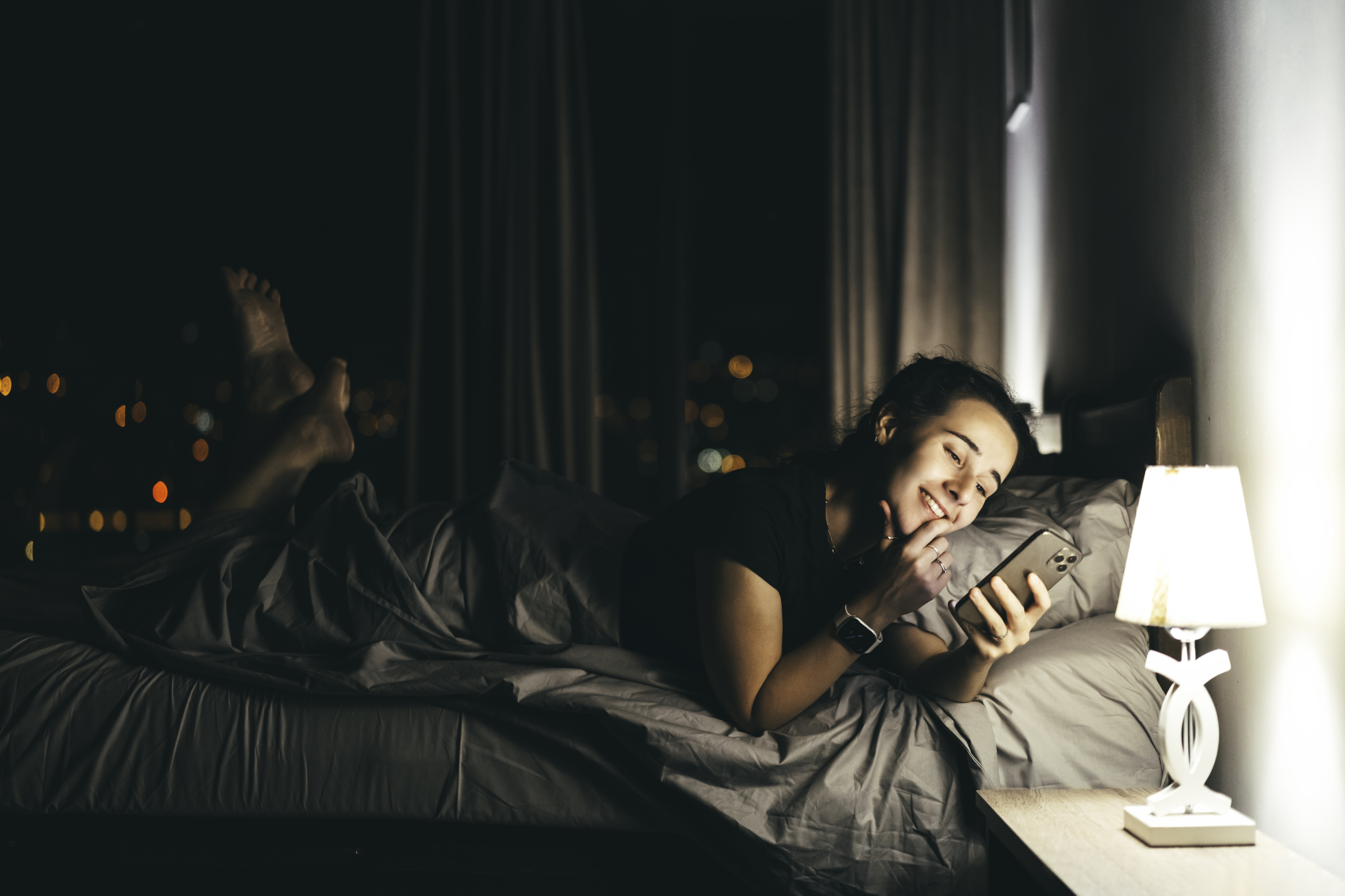 Persona feliz tumbada en la cama sujetando su teléfono | Foto: Getty Images