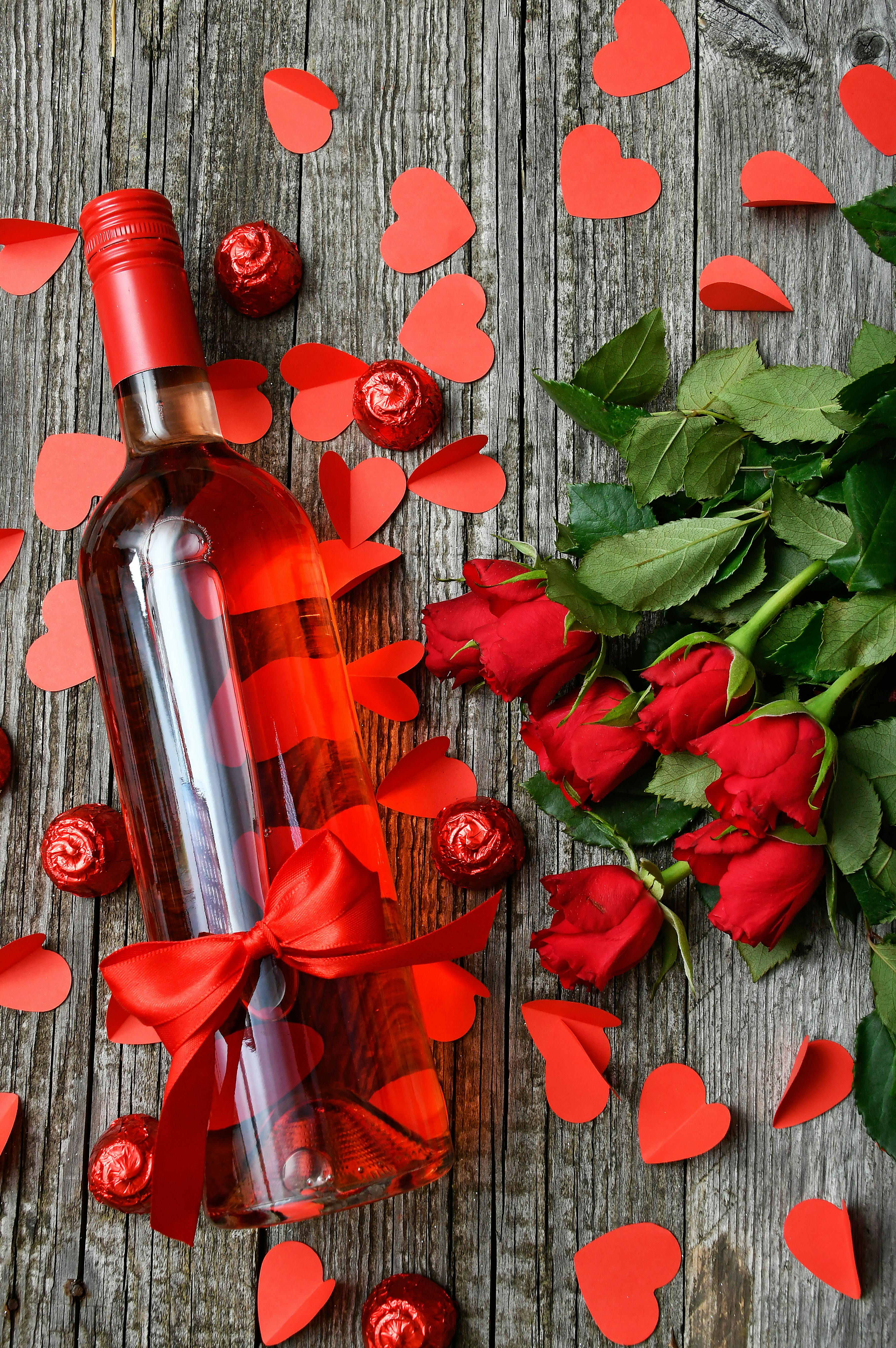 Una botella de vino rodeada de rosas rojas | Fuente: Pexels