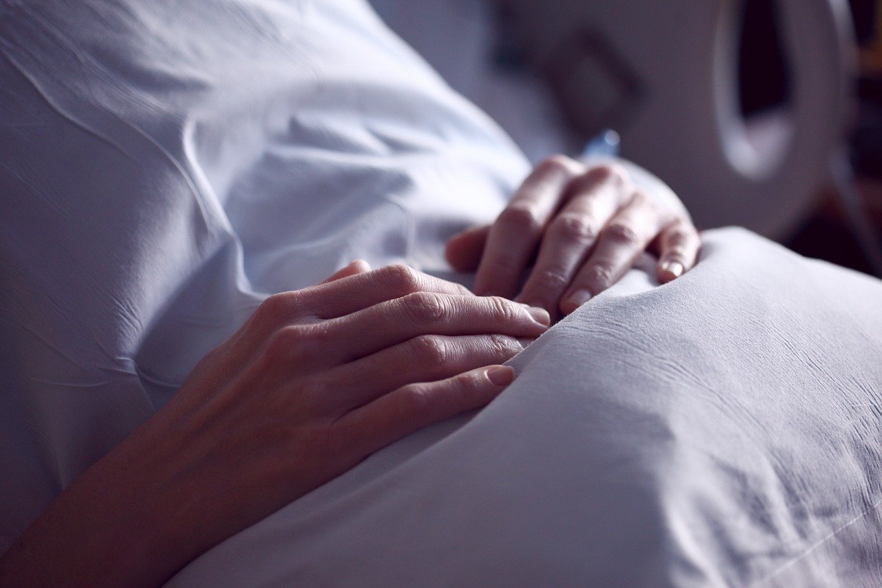 Mujer hospitalizada tocándose la panza con las manos. │Foto: Pixabay/Sharon McCutcheon