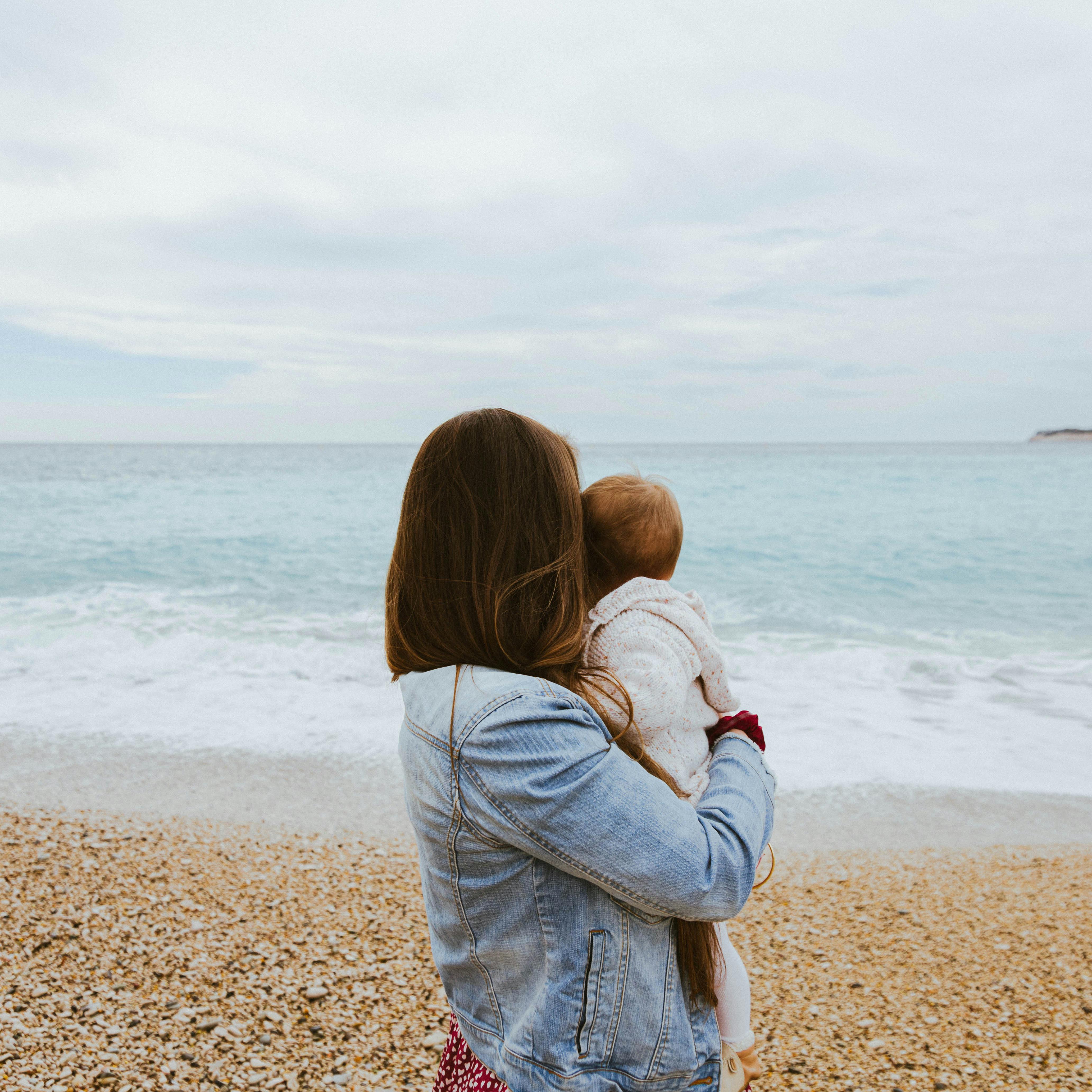 Una mujer con su bebé en brazos en la playa | Fuente: Pexels