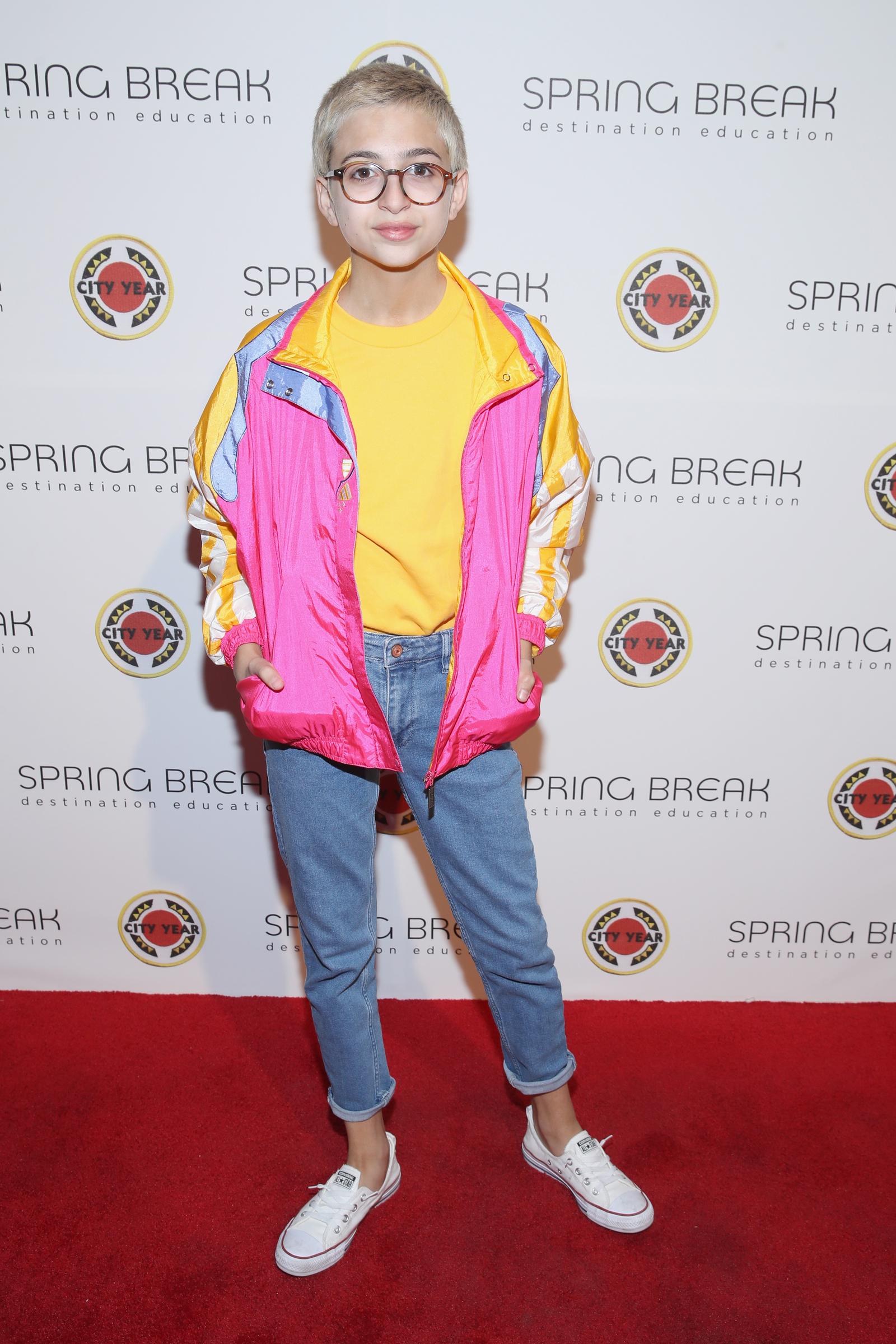 J.J. Totah asiste al evento "Spring Break: Destination Education" de City Year Los Ángeles, celebrado en los Sony Studios de Los Ángeles, California, con una chaqueta de colores vivos —rosa, amarillo y azul— sobre una camiseta amarilla, combinada con unos vaqueros con vuelta, zapatillas blancas y gafas redondas. | Fuente: Getty Images
