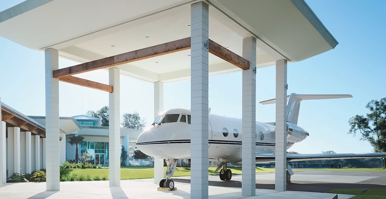 Un jet privado está aparcado bajo un hangar cubierto junto a la casa, lo que muestra lo mucho que se integró la aviación en el diseño de la propiedad. | Fuente: YouTube/@Therichest