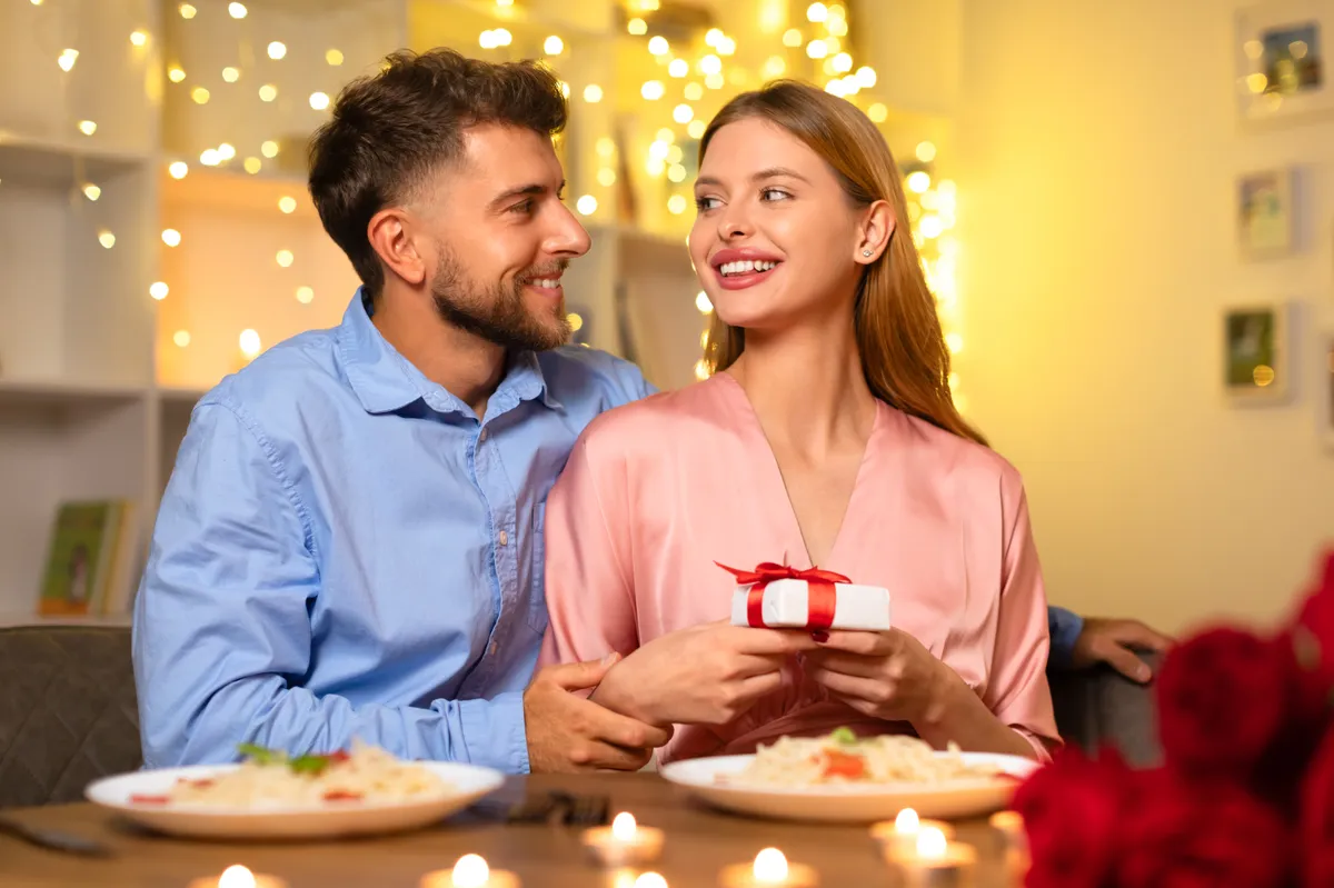 Una pareja feliz celebrando su aniversario durante una cena a la luz de las velas | Fuente: Getty Images