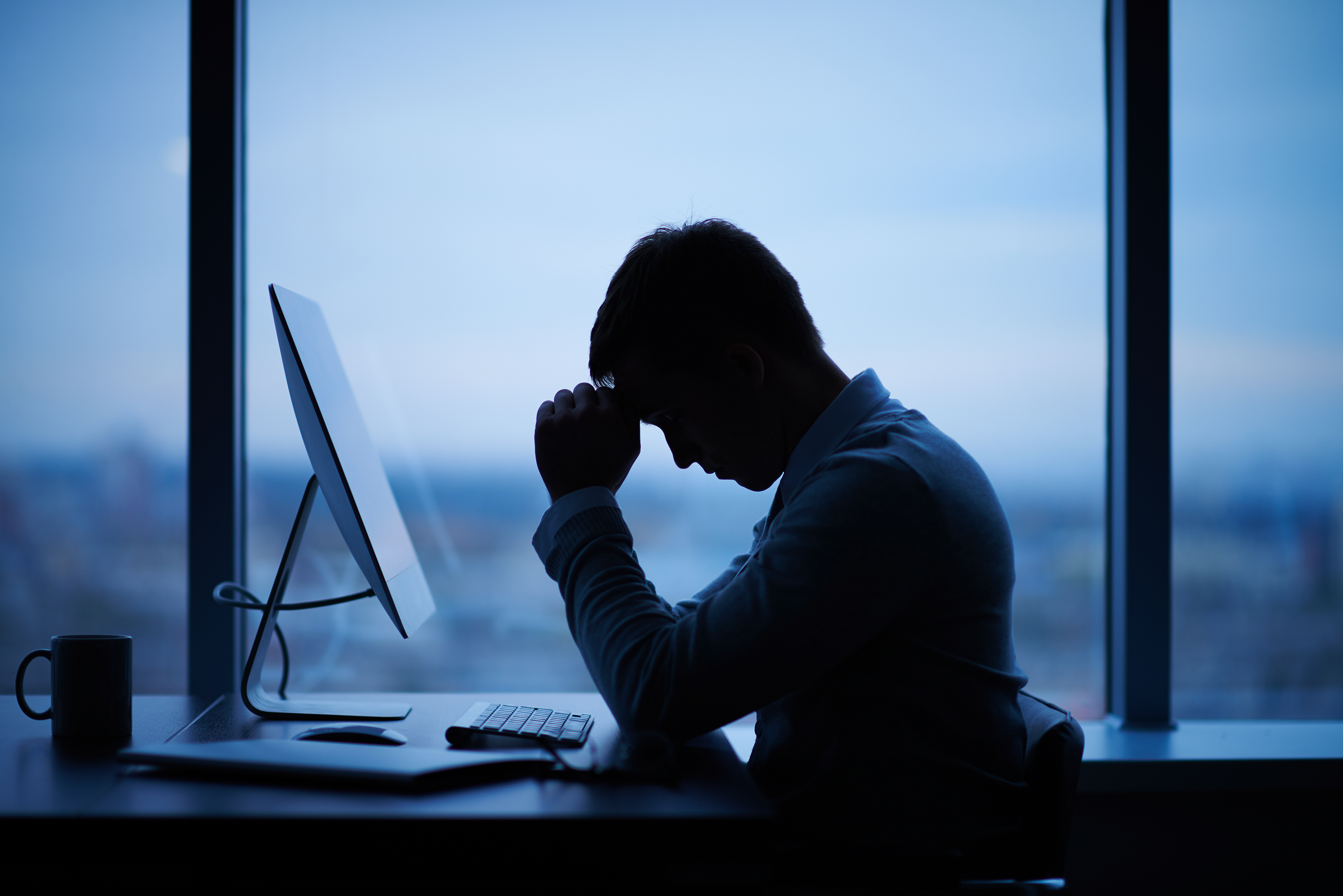Hombre cansado sentado delante de un ordenador en la oficina | Foto: Shutterstock