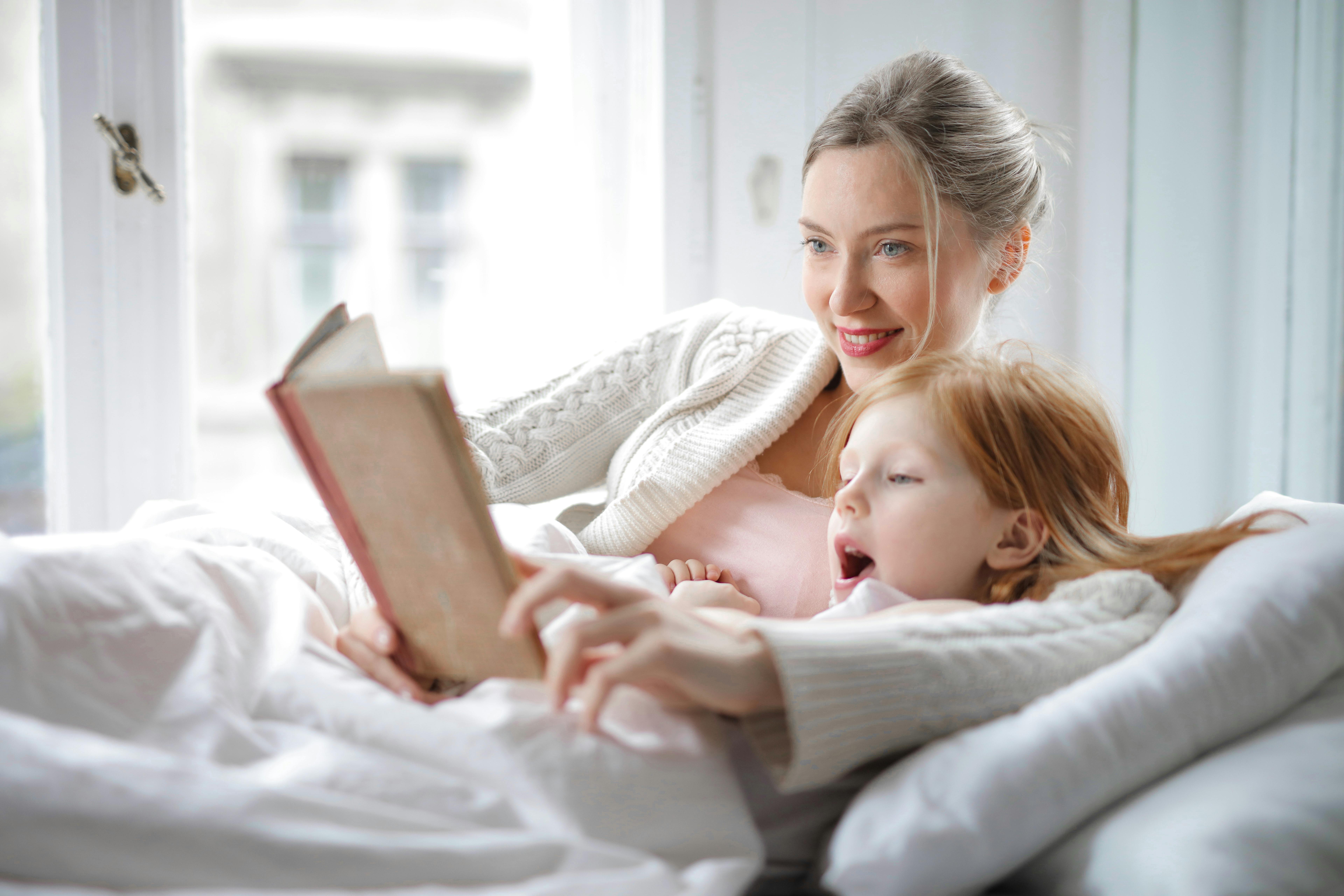 Una mujer feliz y su hija leyendo un cuento | Fuente: Pexels