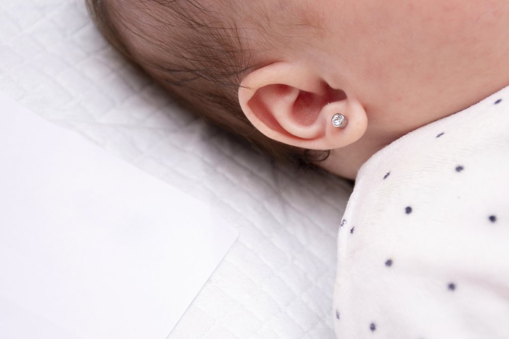 Bebé recién nacida con aretes en sus orejas. | Foto: Shutterstock