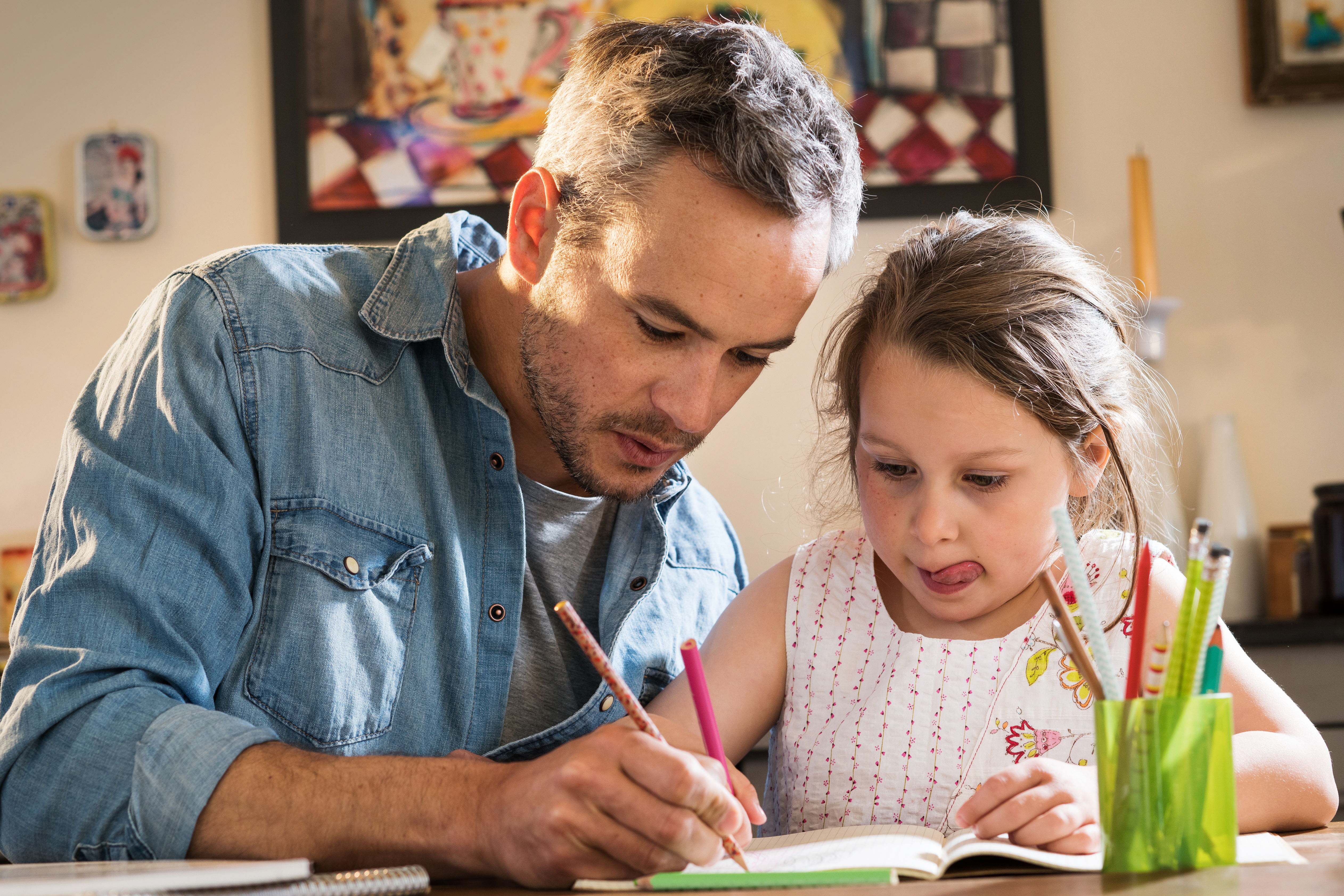 Un hombre ayudando a una niña con los deberes | Foto: Shutterstock