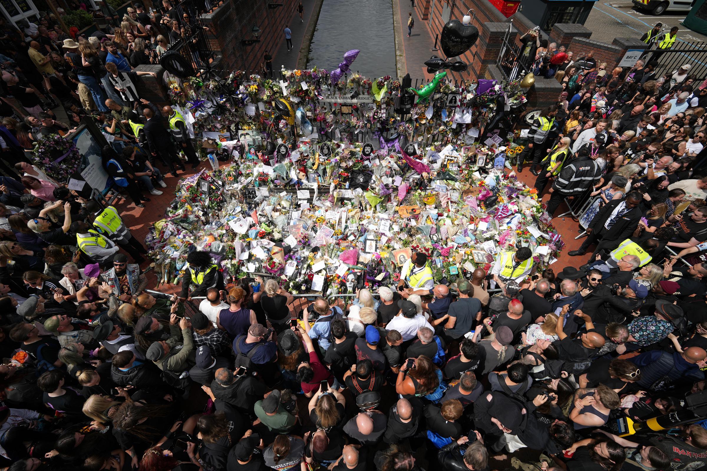 Los fans contemplan los homenajes al fallecido Ozzy Osbourne en el Black Sabbath Bench and Bridge mientras su cortejo fúnebre recorre Birmingham el 30 de julio de 2025, en Birmingham, Inglaterra | Fuente: Getty Images