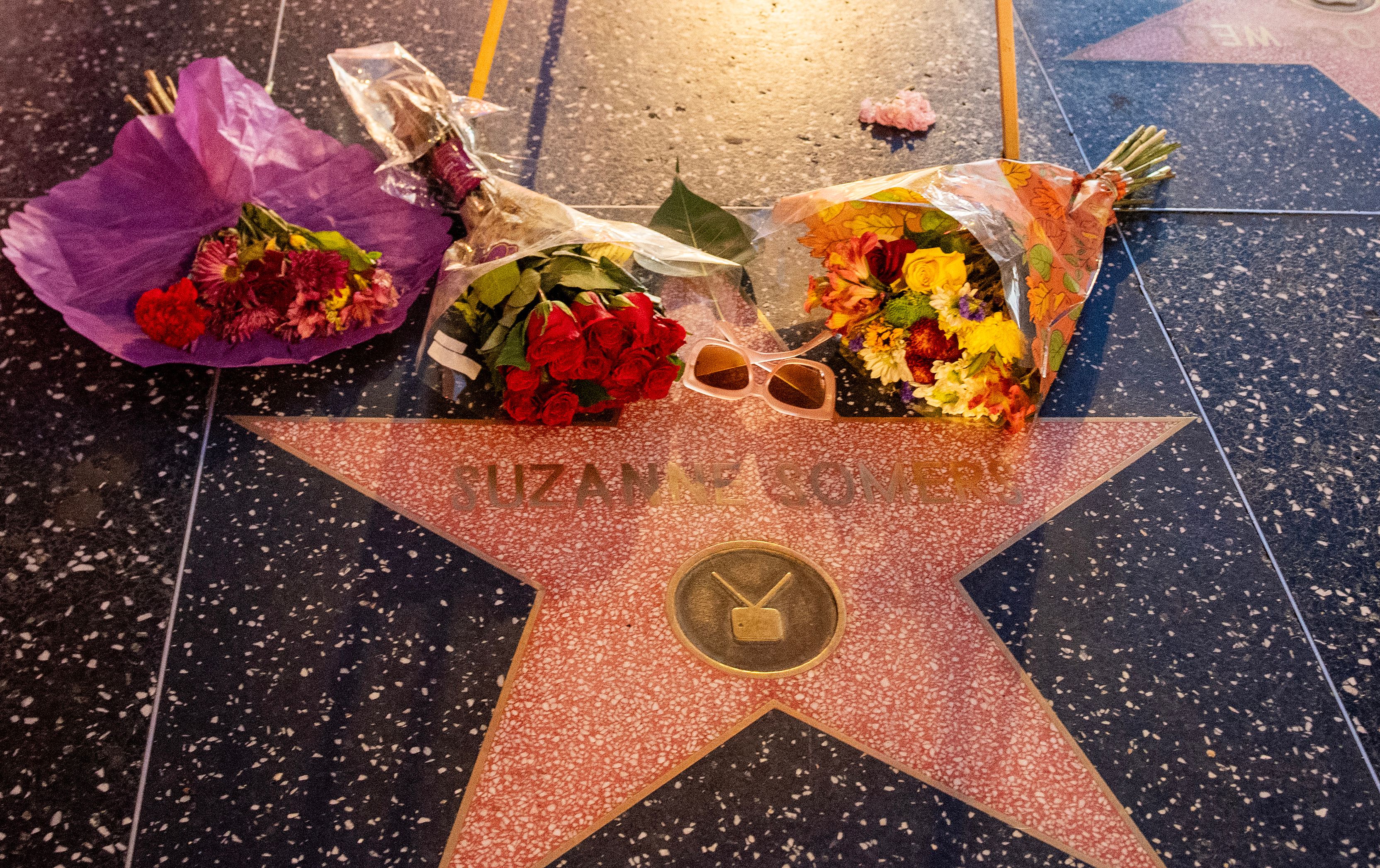 Ramos de flores y unas gafas de sol colocados sobre la estrella del Paseo de la Fama de Hollywood de Suzanne Somers, colocada en su memoria, en Hollywood, California, el 16 de octubre de 2023. | Foto: Getty Images