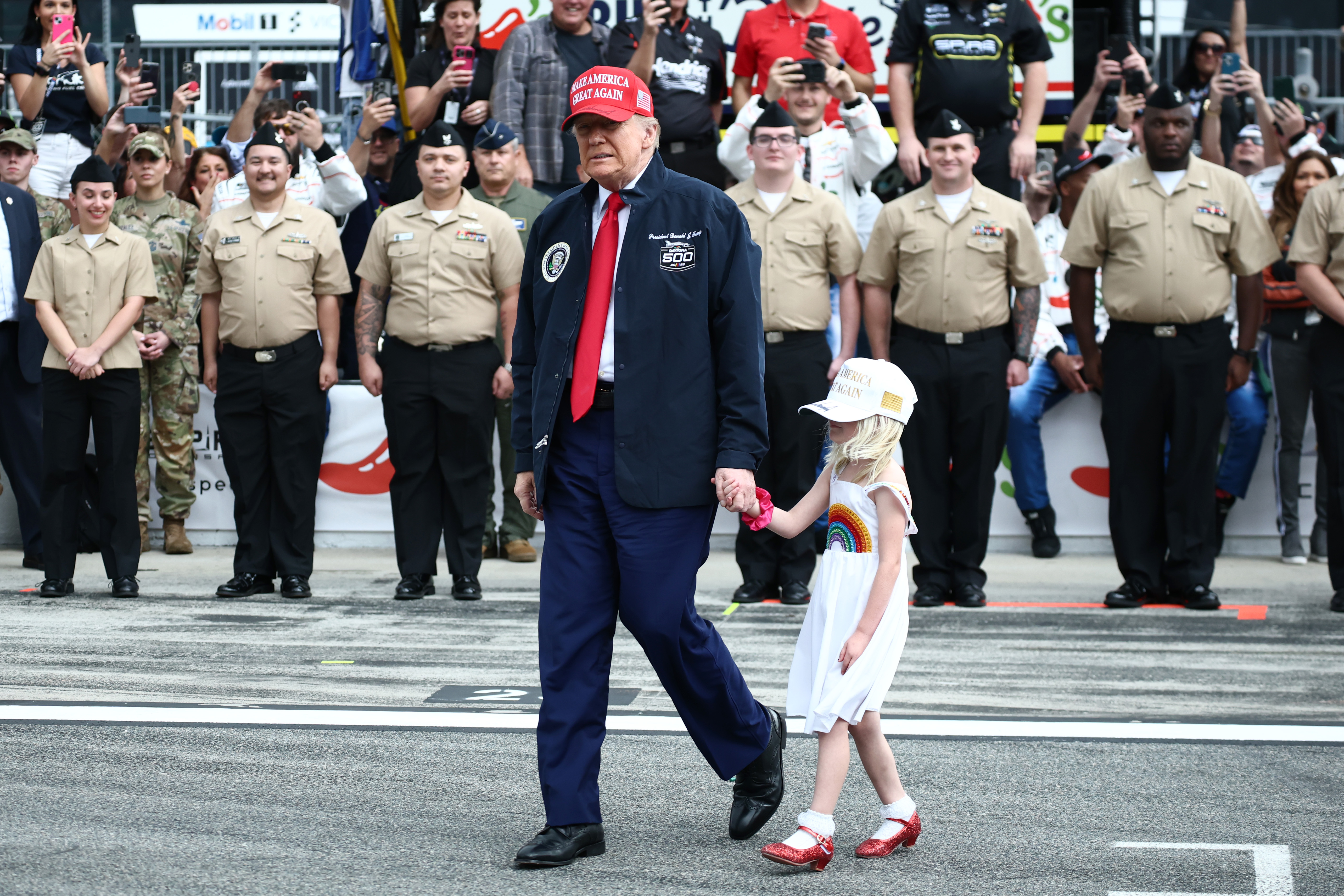 El presidente de EE.UU., Donald Trump, y su nieta aparecen en una foto caminando por la parrilla antes de la NASCAR Cup Series Daytona 500 en el Daytona International Speedway el 16 de febrero de 2025, en Daytona Beach, Florida | Fuente: Getty Images