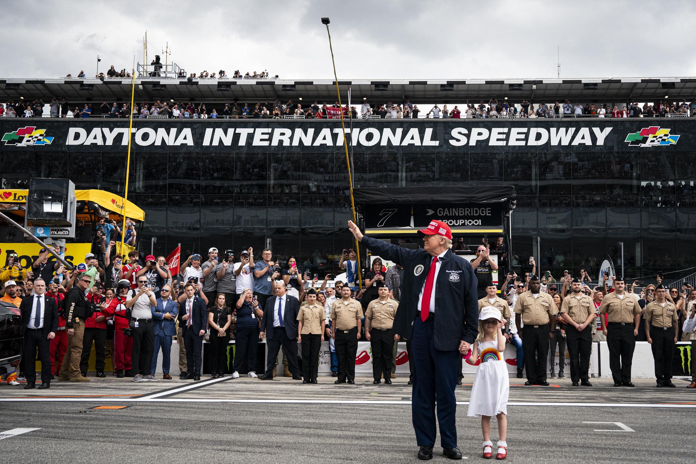 El presidente Donald Trump, acompañado de su nieta Carolina Trump, saluda a los asistentes antes de montarse en la limusina presidencial antes del comienzo de la carrera de Nascar Daytona 500 en Daytona International Speedway en Daytona Beach, Florida, el 16 de febrero de 2025 | Fuente: Getty Images