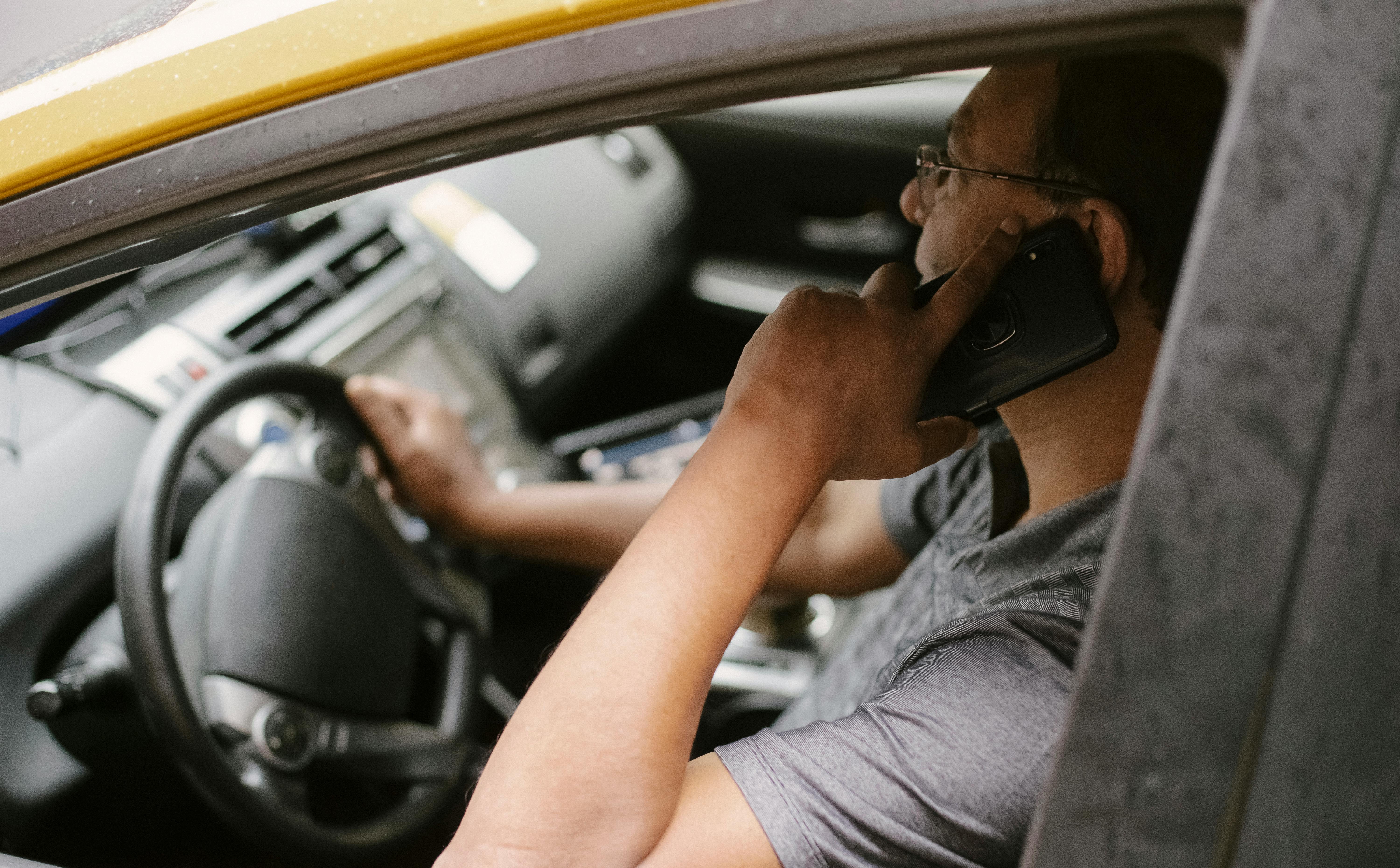 Hombre usando el teléfono mientras conduce | Foto: Pexels