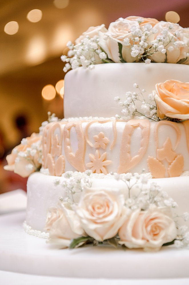 Hermoso pastel de bodas decorado con rosas naranjas. | Fuente: Shutterstock