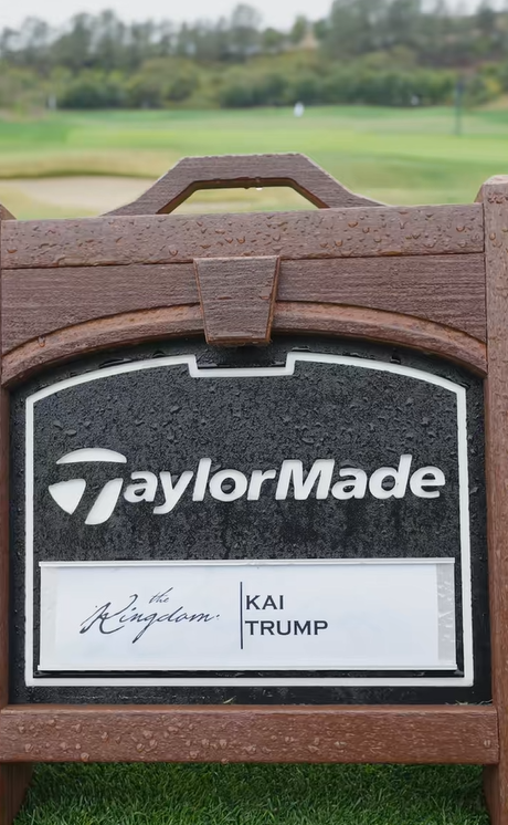 Un cartel de TaylorMade con el nombre de Kai Trump se alza sobre un fairway borroso, salpicado de gotas de lluvia en su marco de madera | Fuente: Tiktok/thekaitrumpgolfer