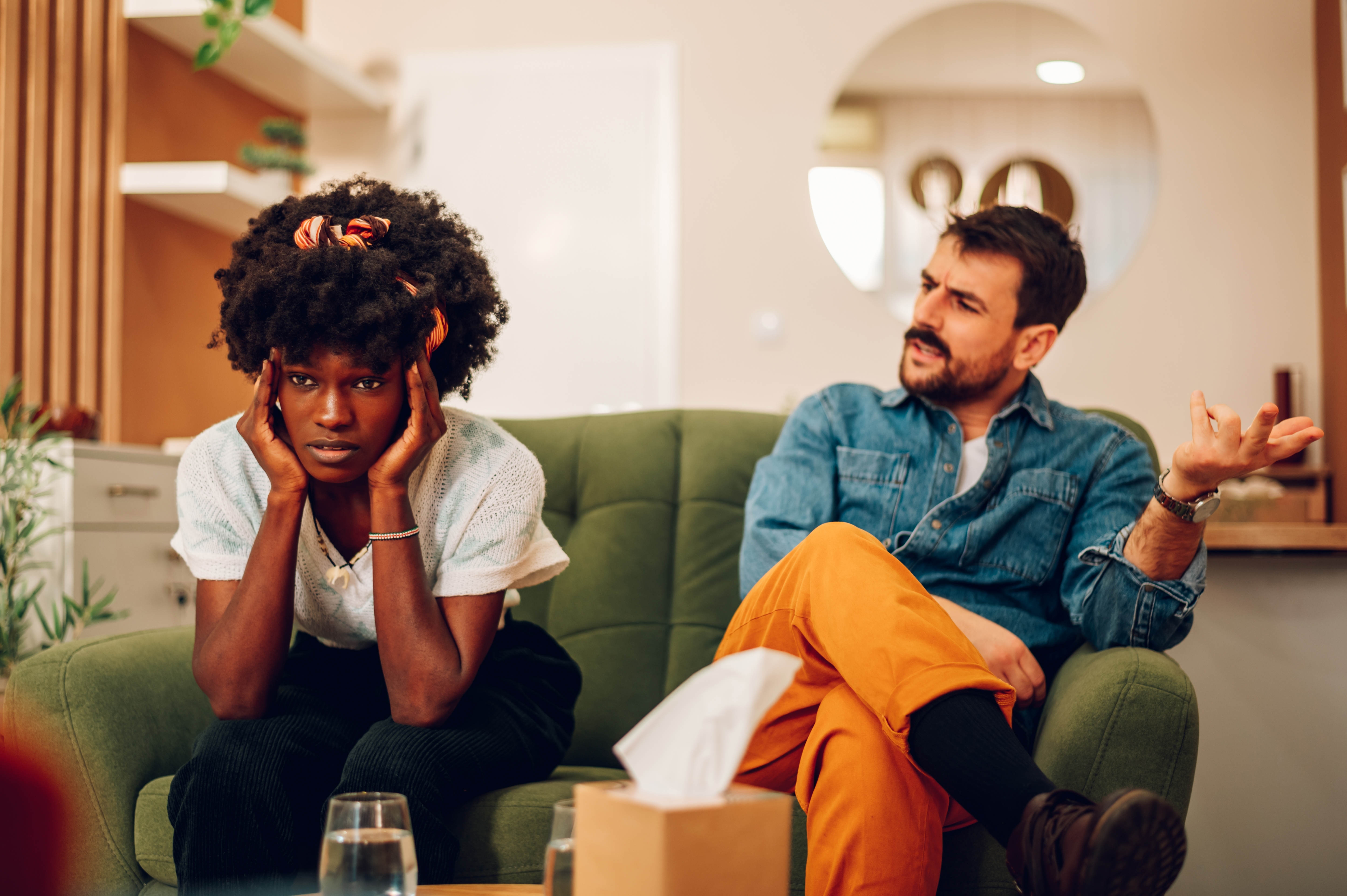 Un hombre blanco y una mujer negra discutiendo sentados en un sofá | Foto: Shutterstock