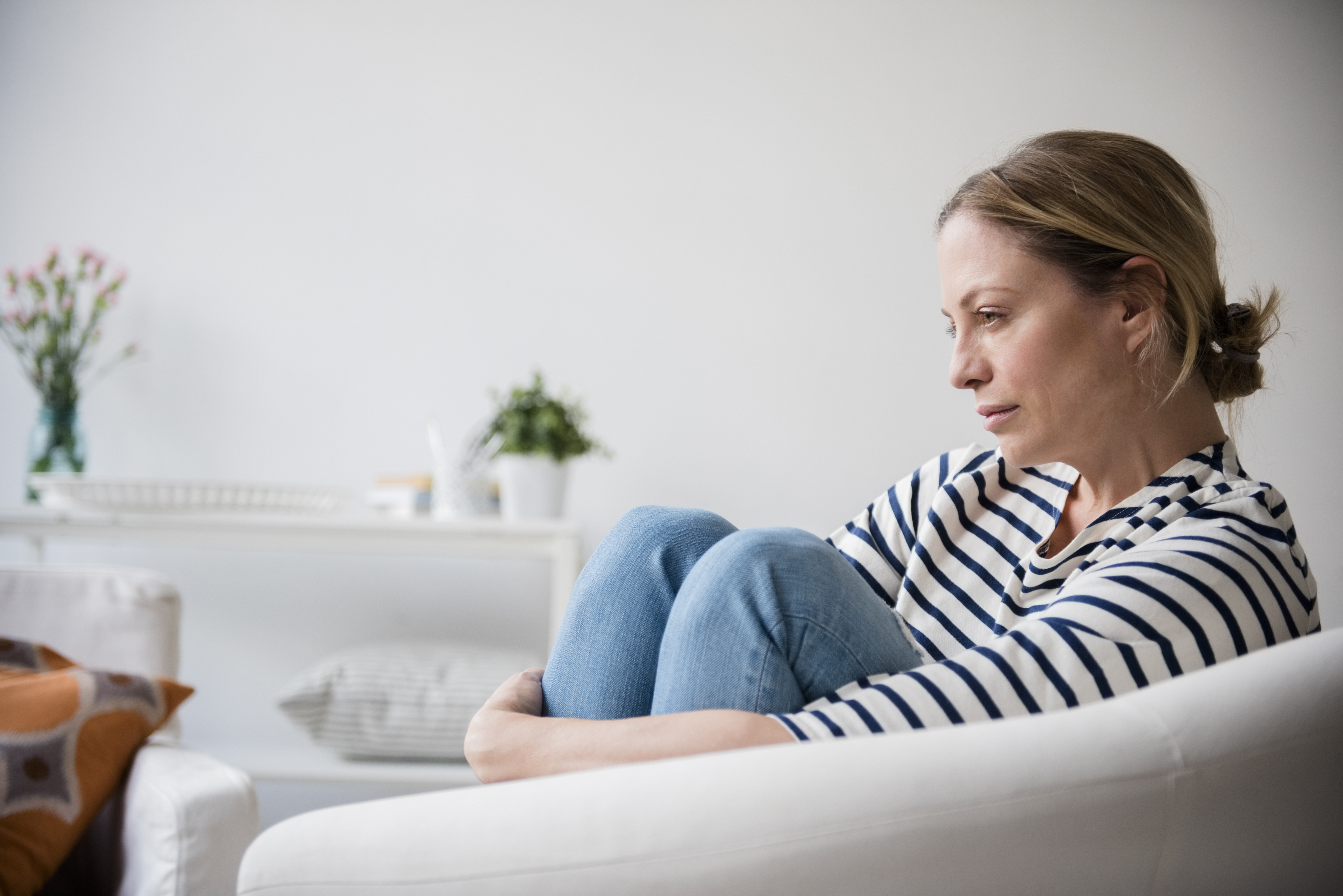 Mujer caucásica sentada en un sillón sujetándose las piernas | Fuente: Getty Images