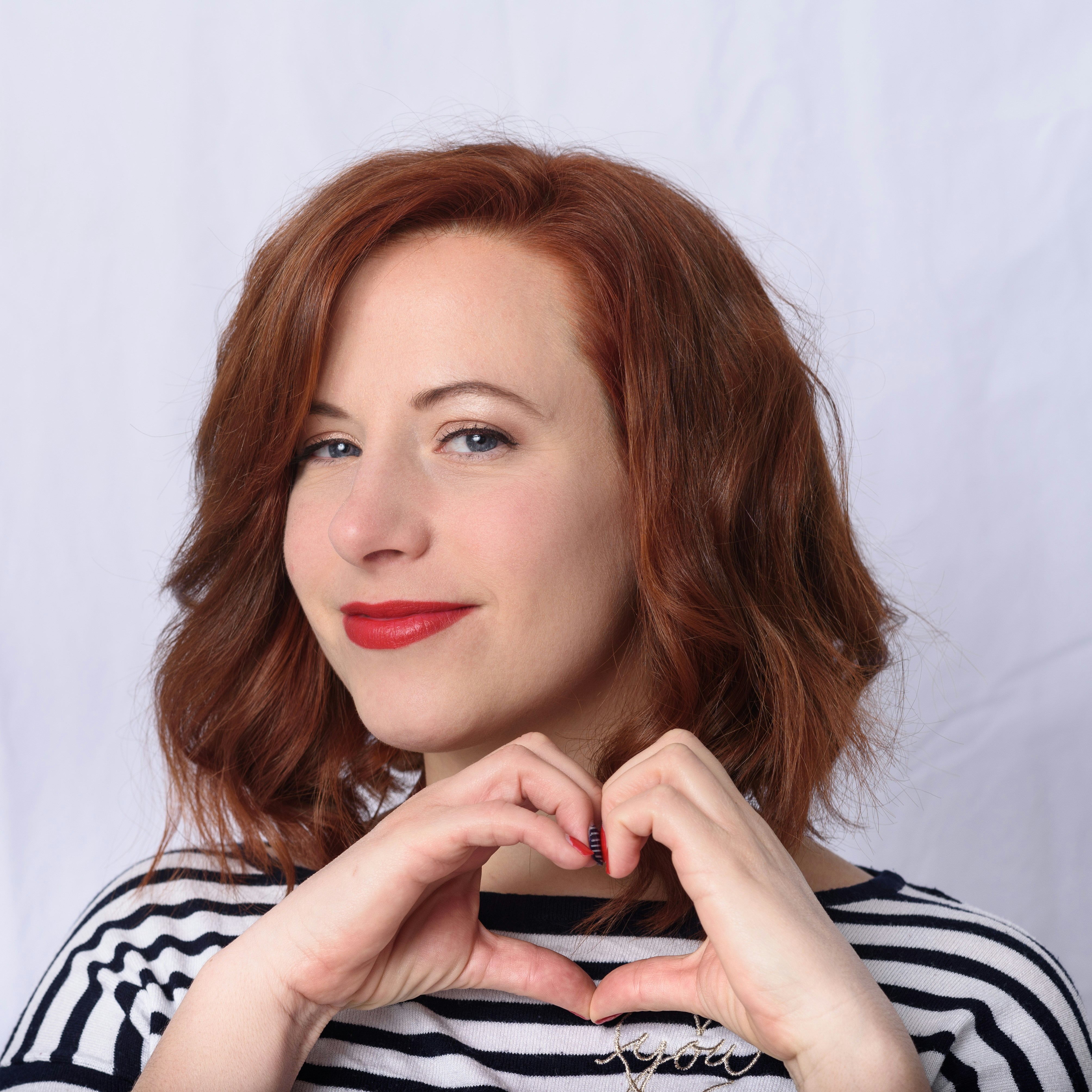 Una mujer sonriente firmando un corazón con las manos | Fuente: Unsplash