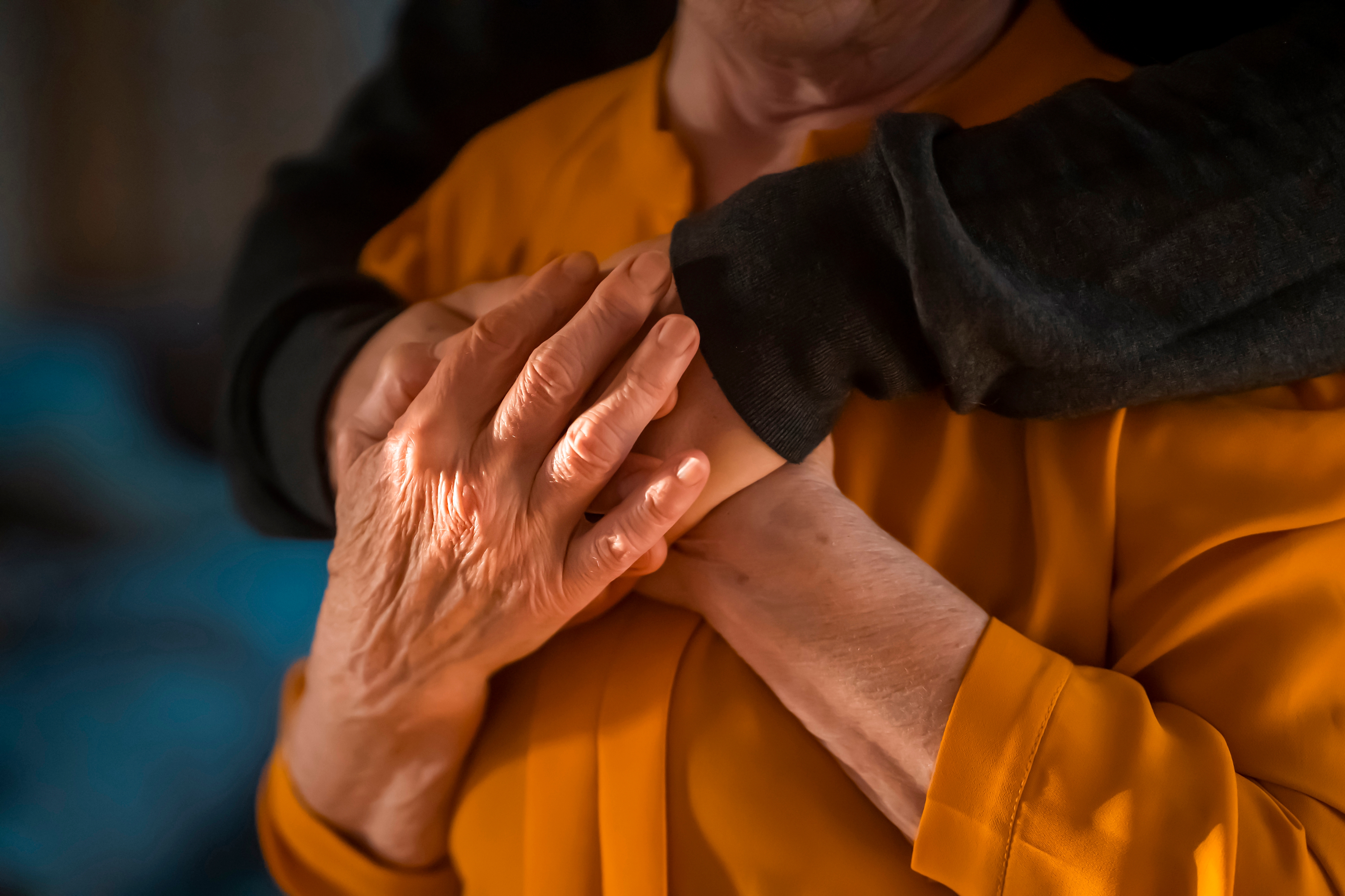 Una madre mayor cogiendo las manos de su hijo como gesto de consuelo y apoyo | Foto: Shutterstock