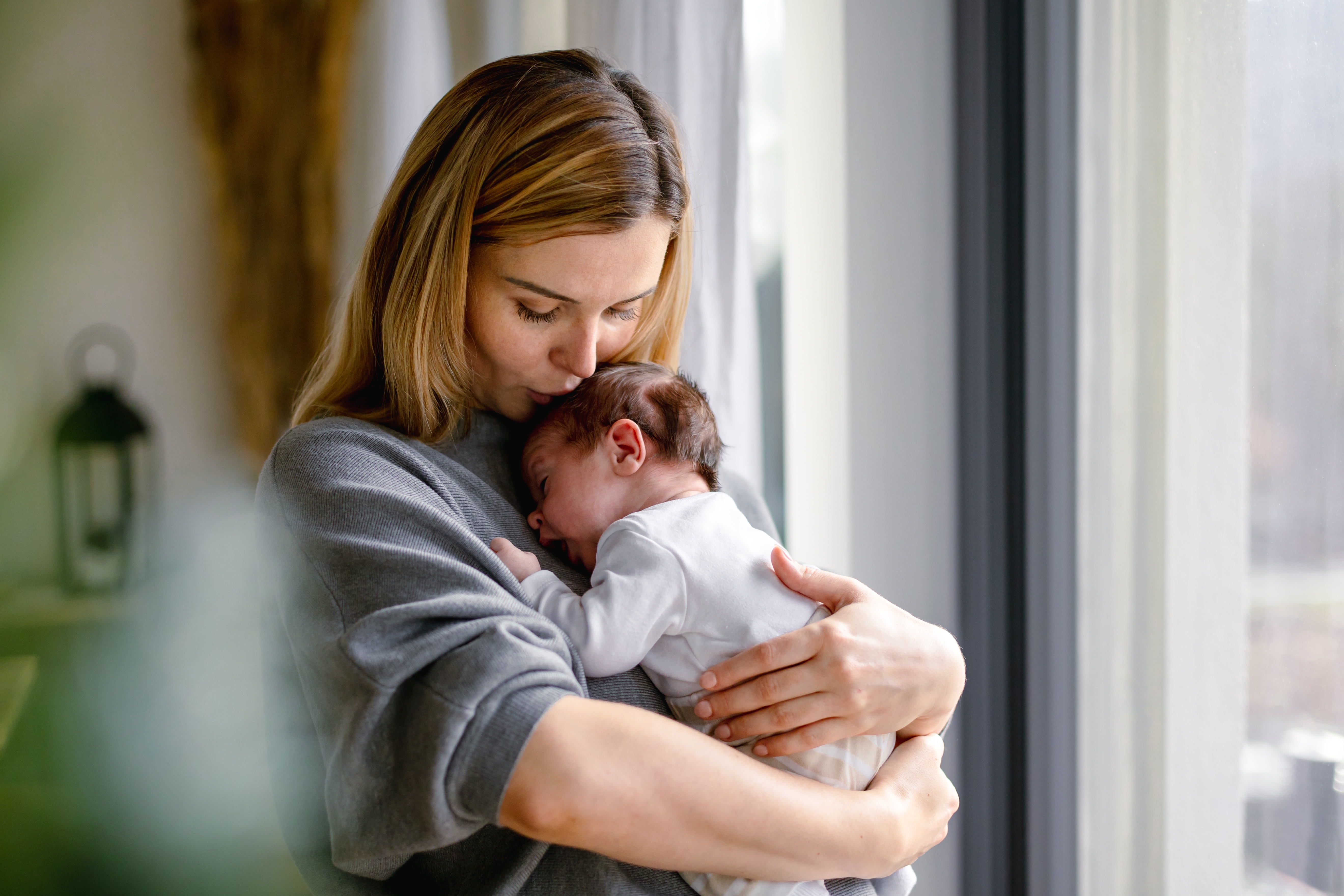 Madre cariñosa abraza a su pequeño bebé en casa | Fuente: Shutterstock.com