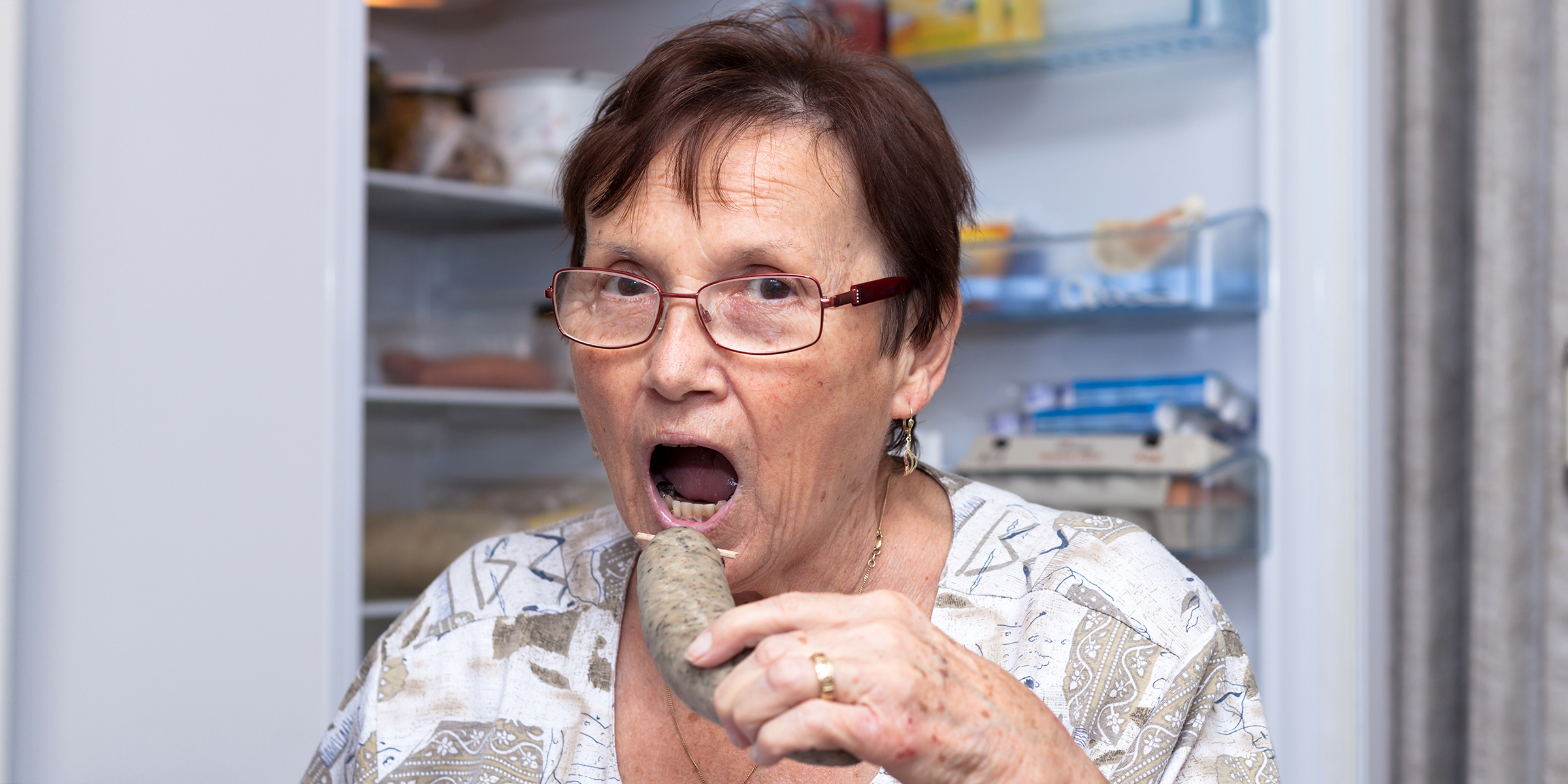 Mujer comiendo delante de la nevera | Fuente: Shutterstock