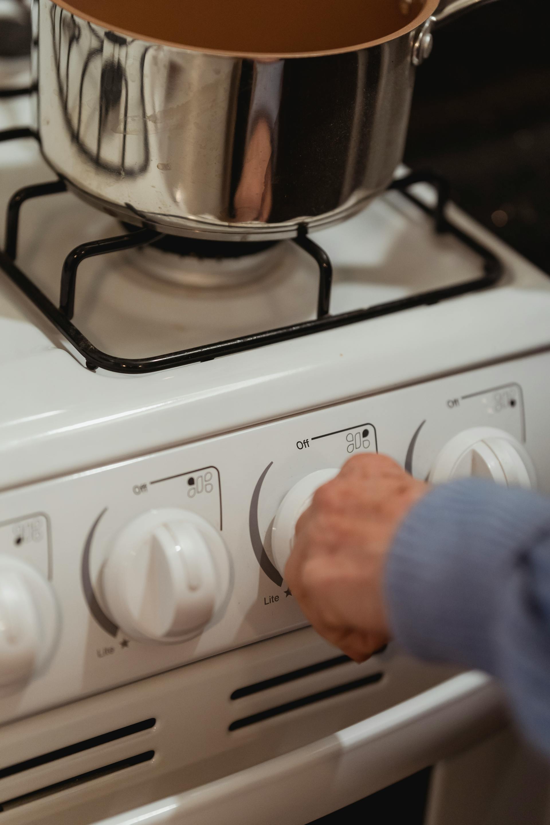 Primer plano de una mujer girando el pomo de una estufa | Fuente: Pexels