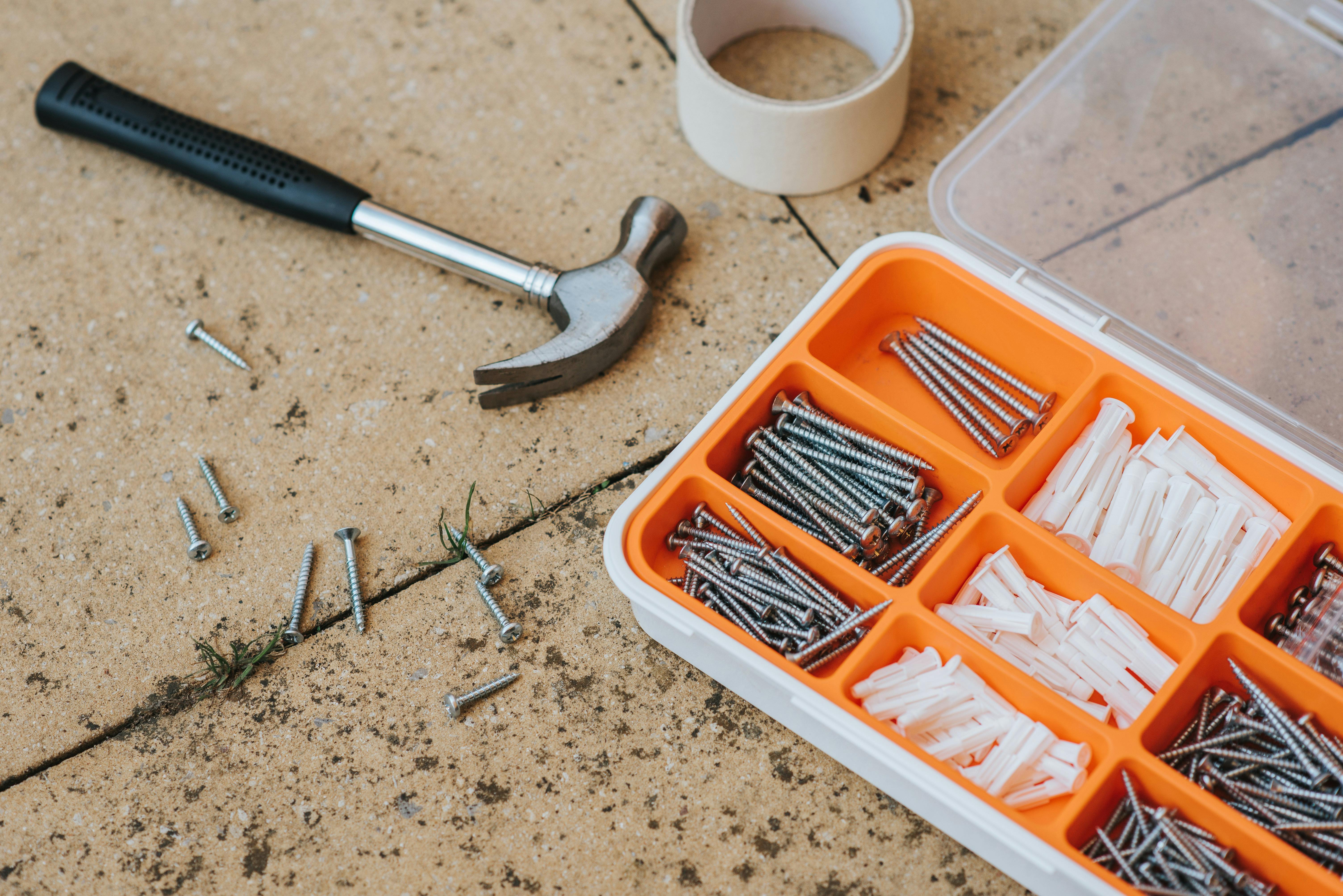 Tornillos y herramientas de reparación en una caja cerca de un martillo | Fuente: Pexels