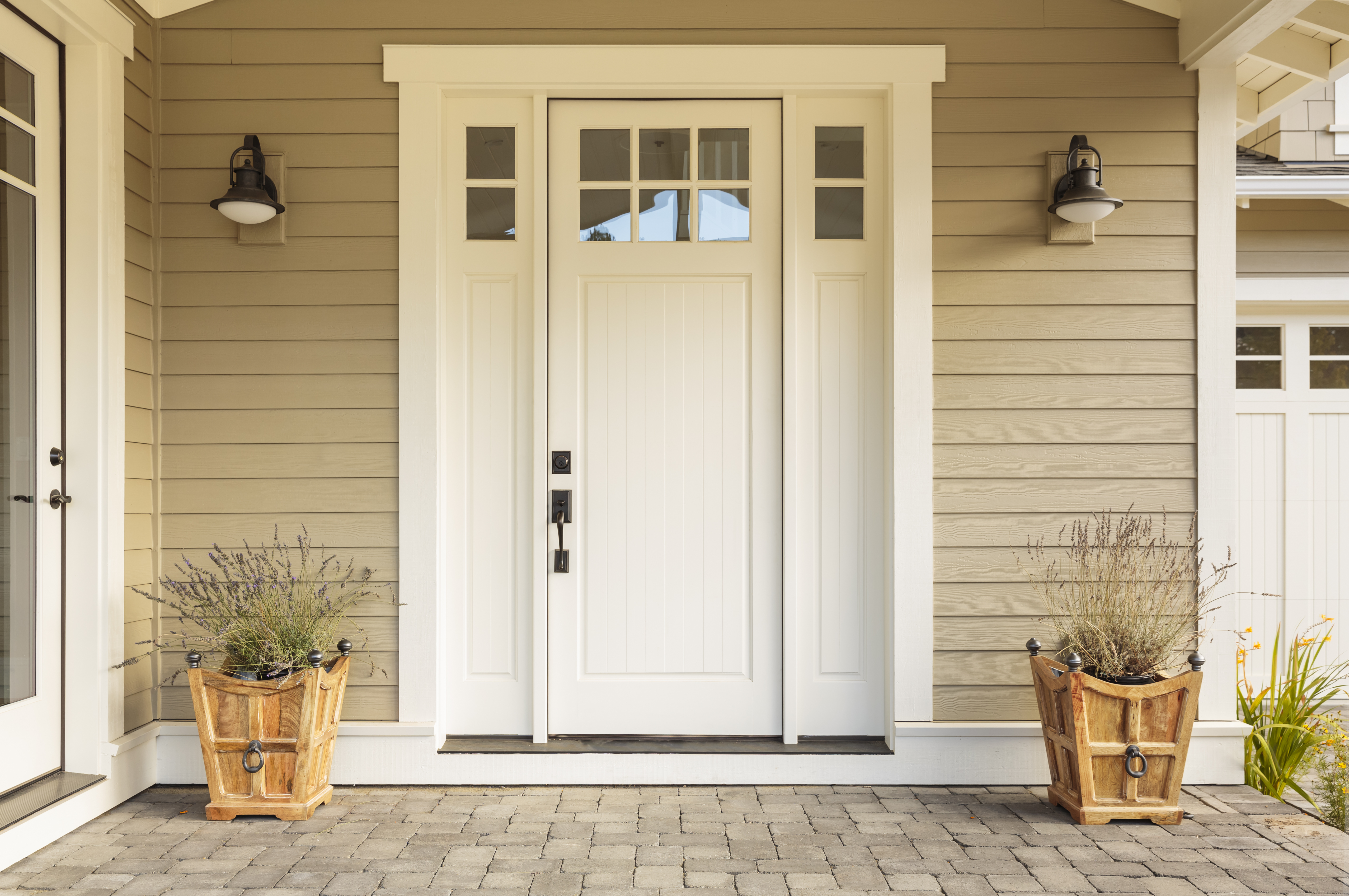 Puerta de entrada blanca con pequeñas ventanas cuadradas decorativas y macetas | Foto: Shutterstock