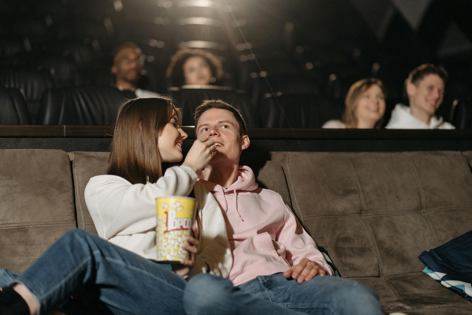 Pareja comiendo palomitas mientras ve una película en un cine | Fuente: Pexels