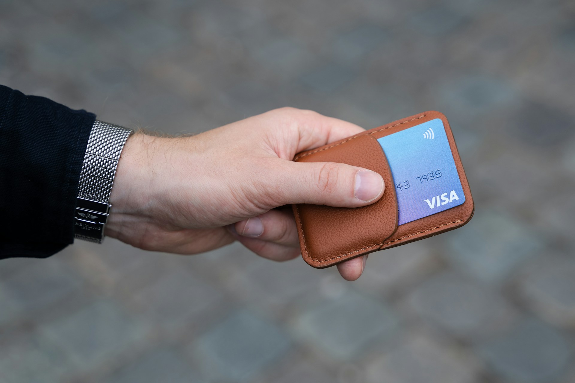 Un hombre sostiene una tarjeta bancaria en un tarjetero de cuero | Fuente: Unsplash