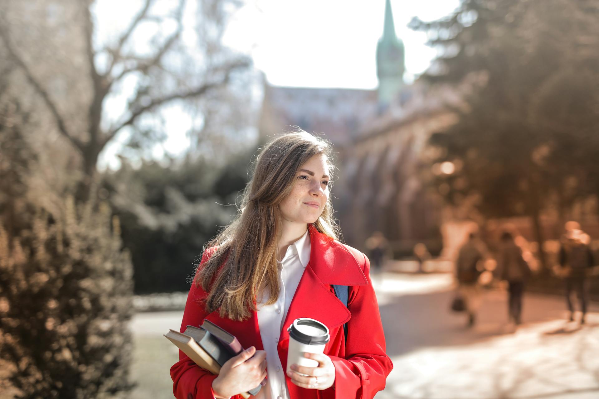 Una mujer en un campus universitario llevando libros | Fuente: Pexels