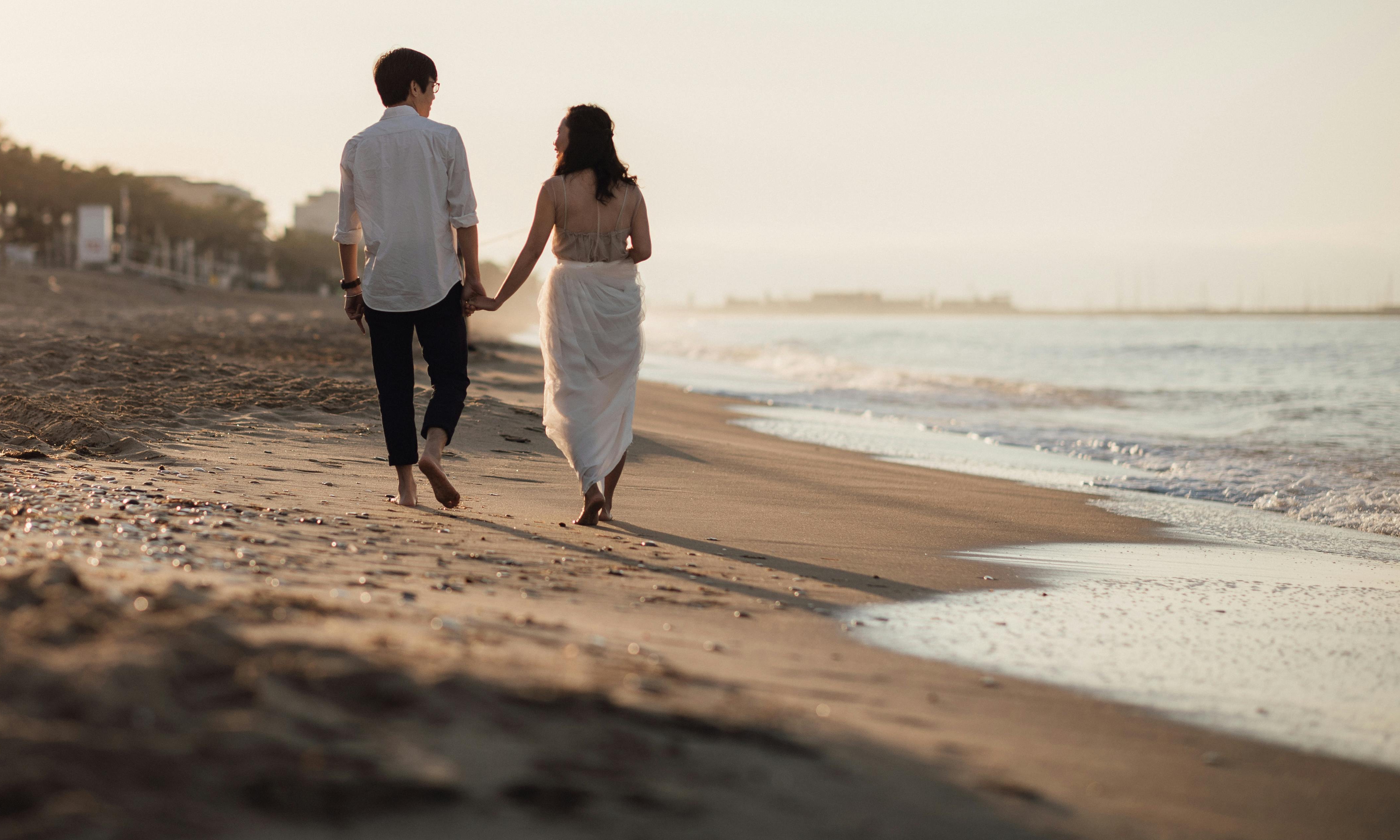 Una pareja paseando de la mano por una playa al atardecer | Fuente: Pexels