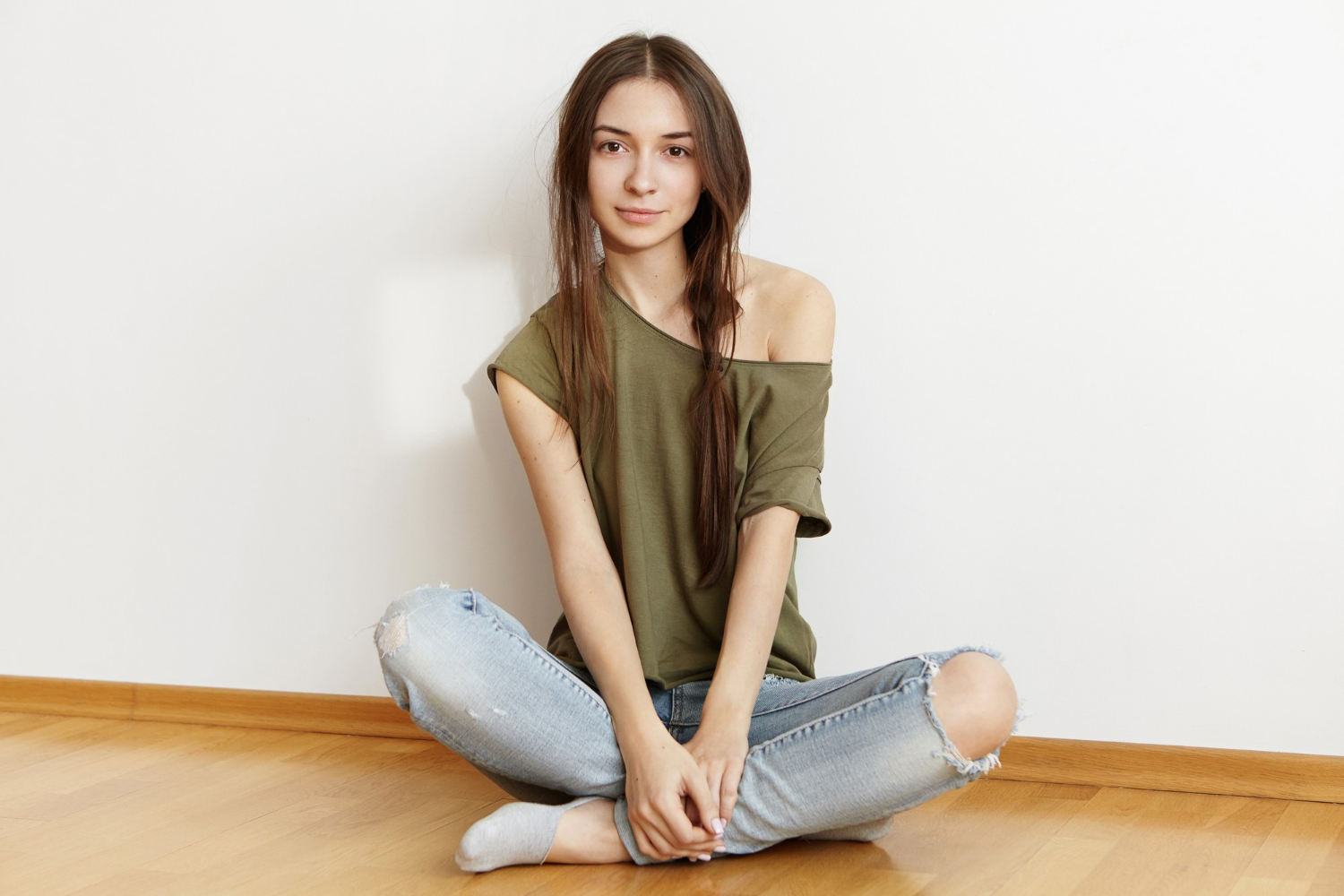 Una alegre adolescente sentada en el suelo y sonriendo | Fuente: Freepik