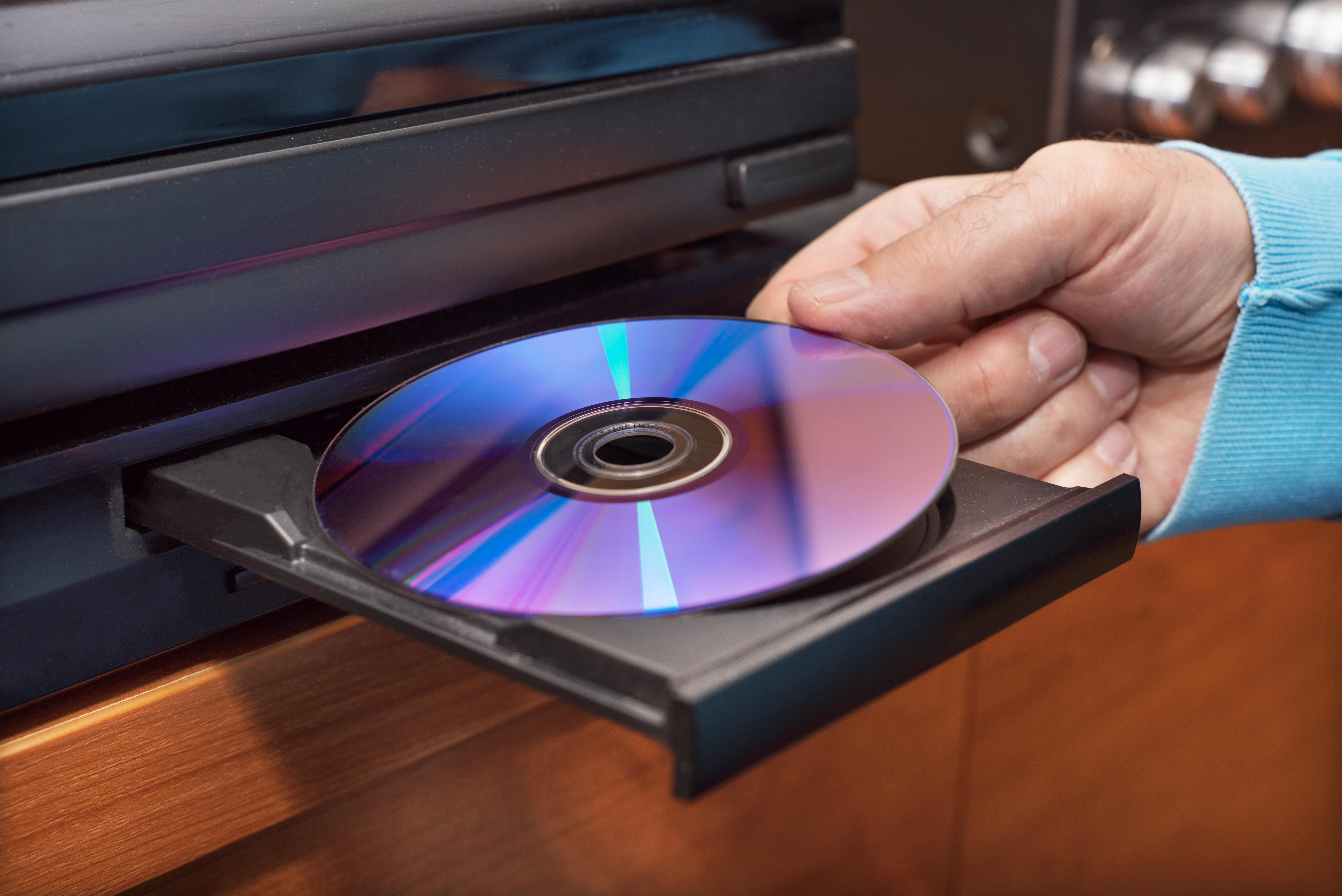Una mano colocando un DVD dentro del reproductor | Foto: Shutterstock